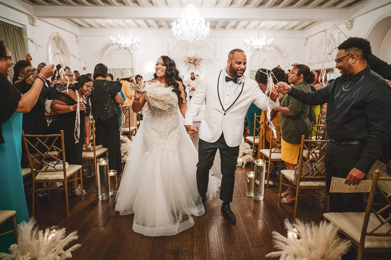 Bride and groom smiling as they walk down the aisle together after saying "I do" while passing their wedding guests.