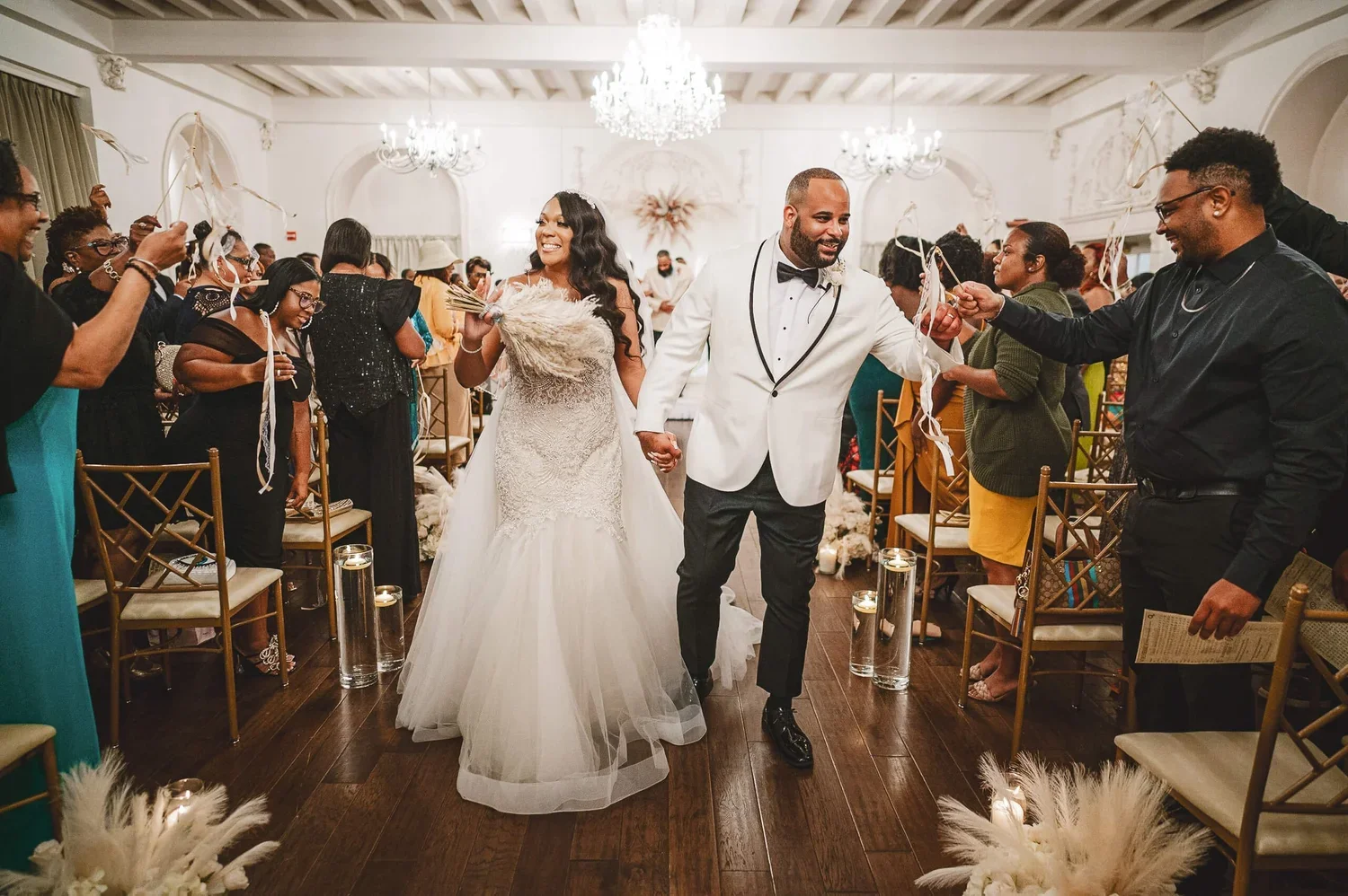 Bride and groom smiling as they walk down the aisle together after saying "I do" while passing their wedding guests.