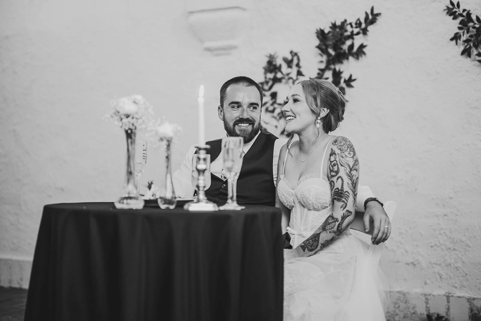 couple laughing during wedding reception toasts, the groom on the left looking lovingly at the bright on the right
