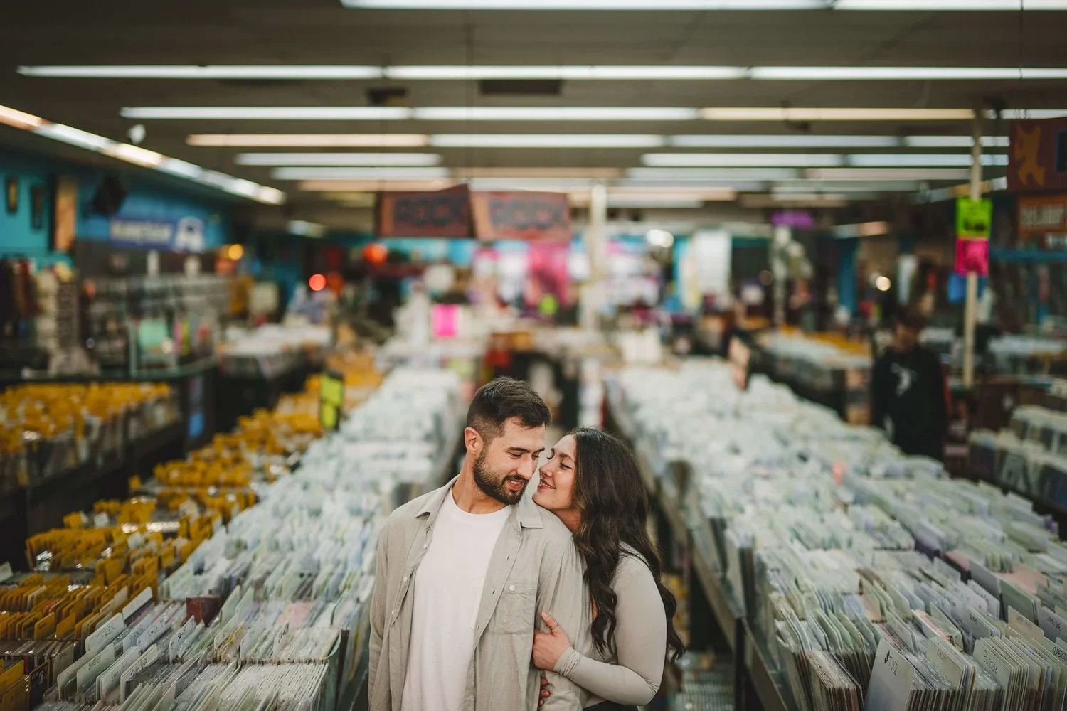 Couple smiling and embracing each other inside a record store during their engagement photoshoot.
