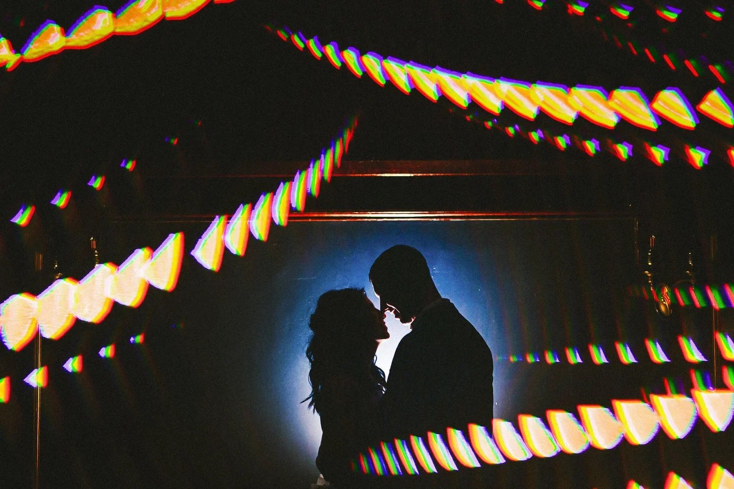 Silhouette of a couple on their wedding day surrounded by bright blurred lights and a glowing atmosphere.
