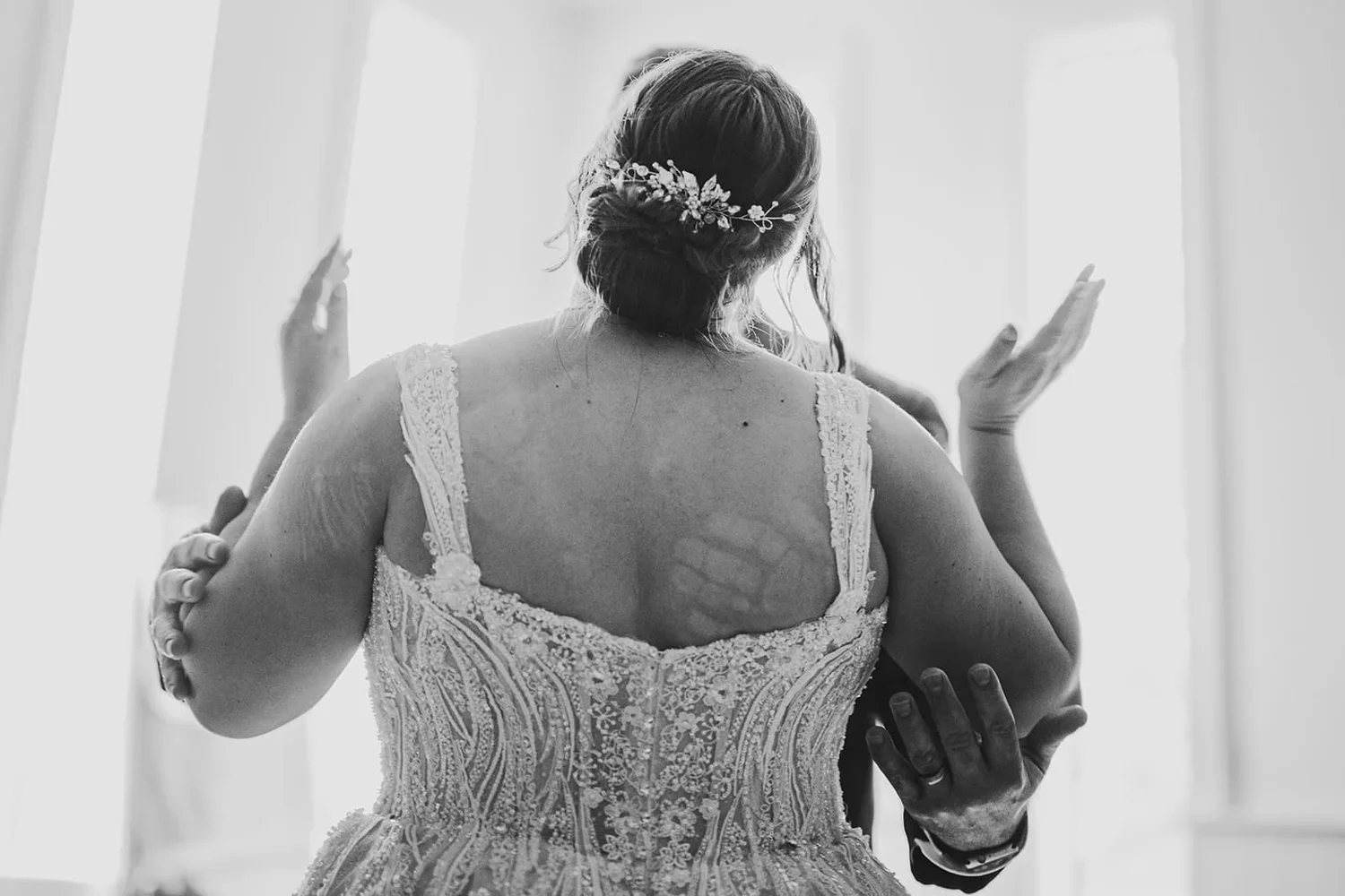 Black and white wedding portrait showing the back of a bride on her wedding day.