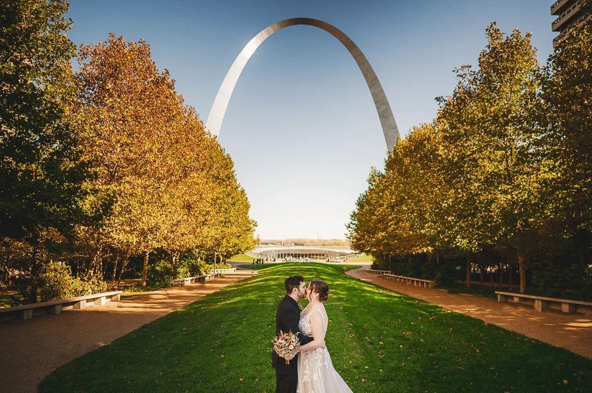 Bride and groom on their wedding day with the St. Louis Gateway Arch and blue sky in the background.