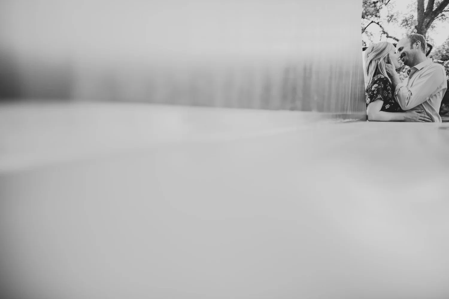Black and white engagement portrait of a couple smiling and embracing each other.