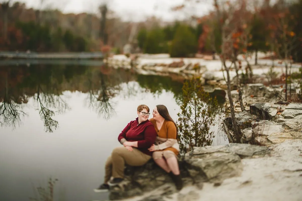 Couple sharing a quiet moment by the shoreline during their autumn engagement session.