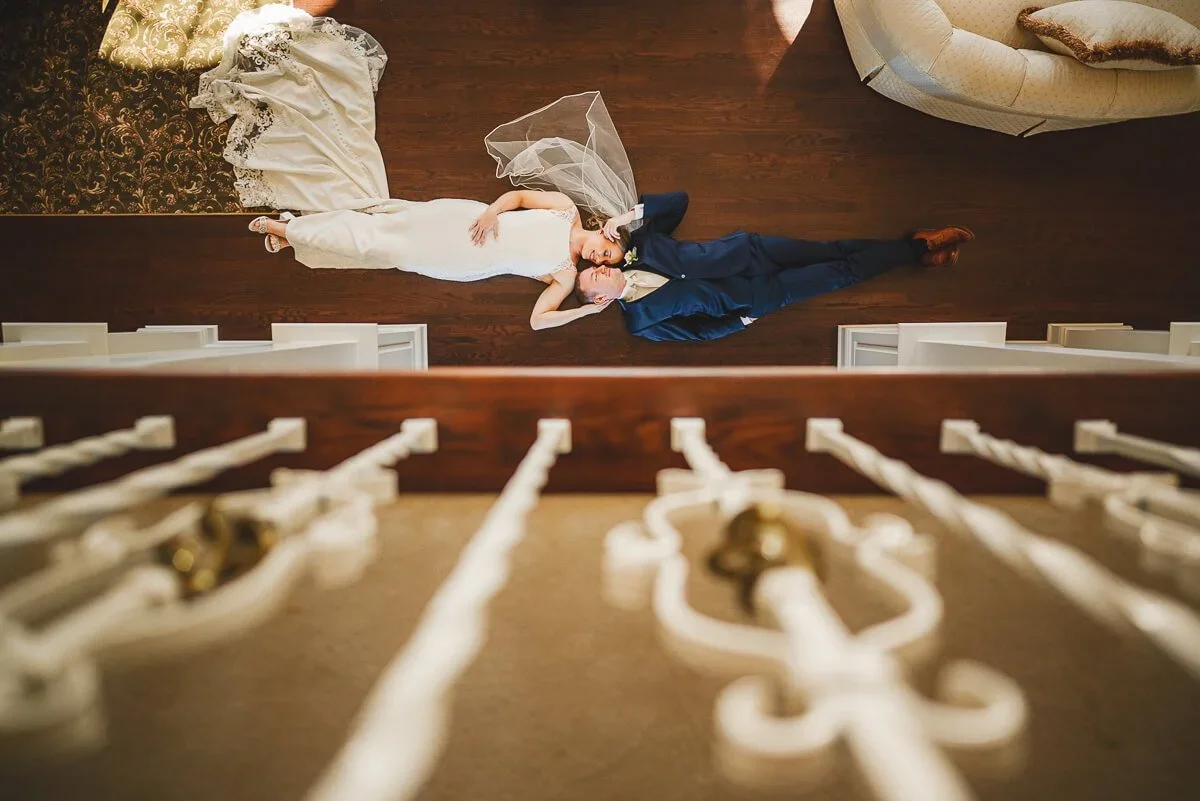 Overhead view of a bride and groom lying together in their wedding attire on their wedding day.