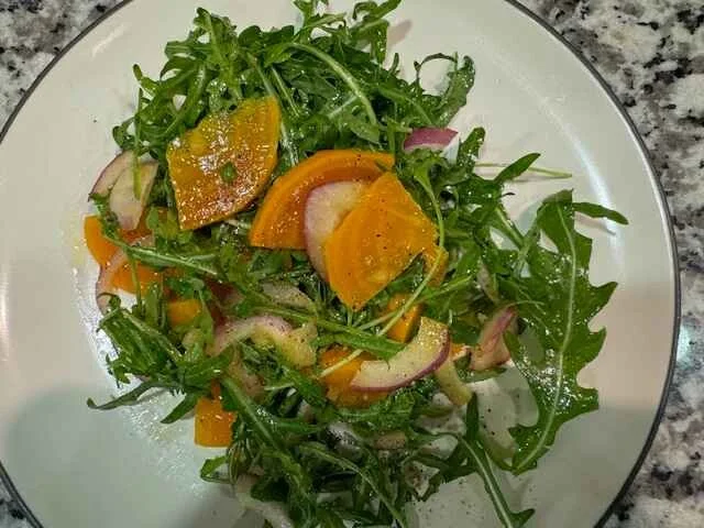 Fresh arugula salad with sliced golden beets, red onion, and vinaigrette
