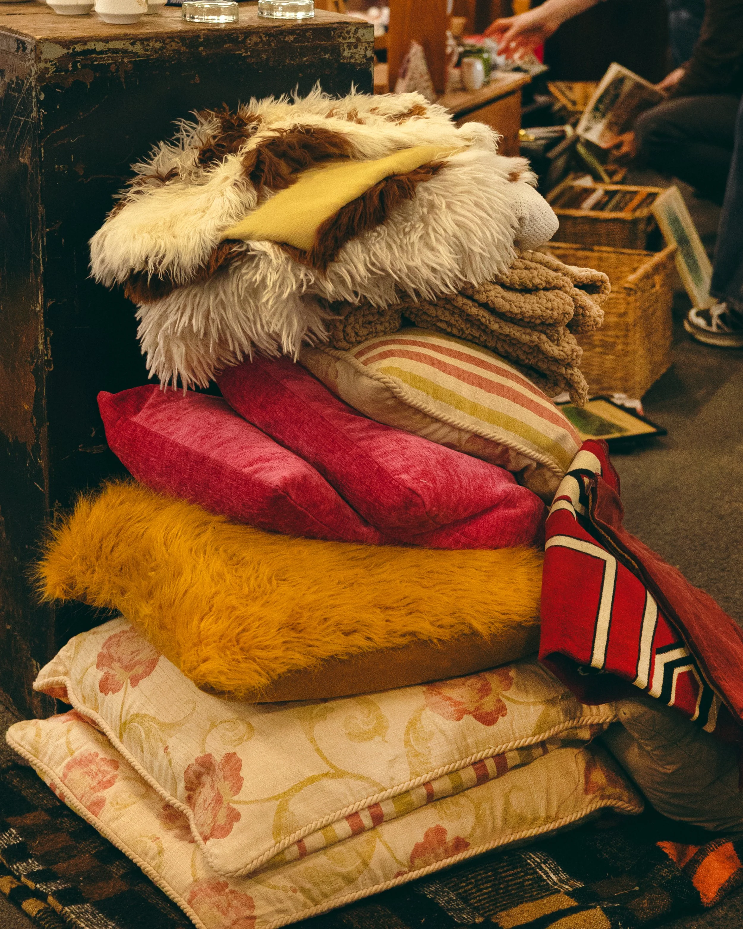 Stacked assorted pillows and blankets at a thrift store.
