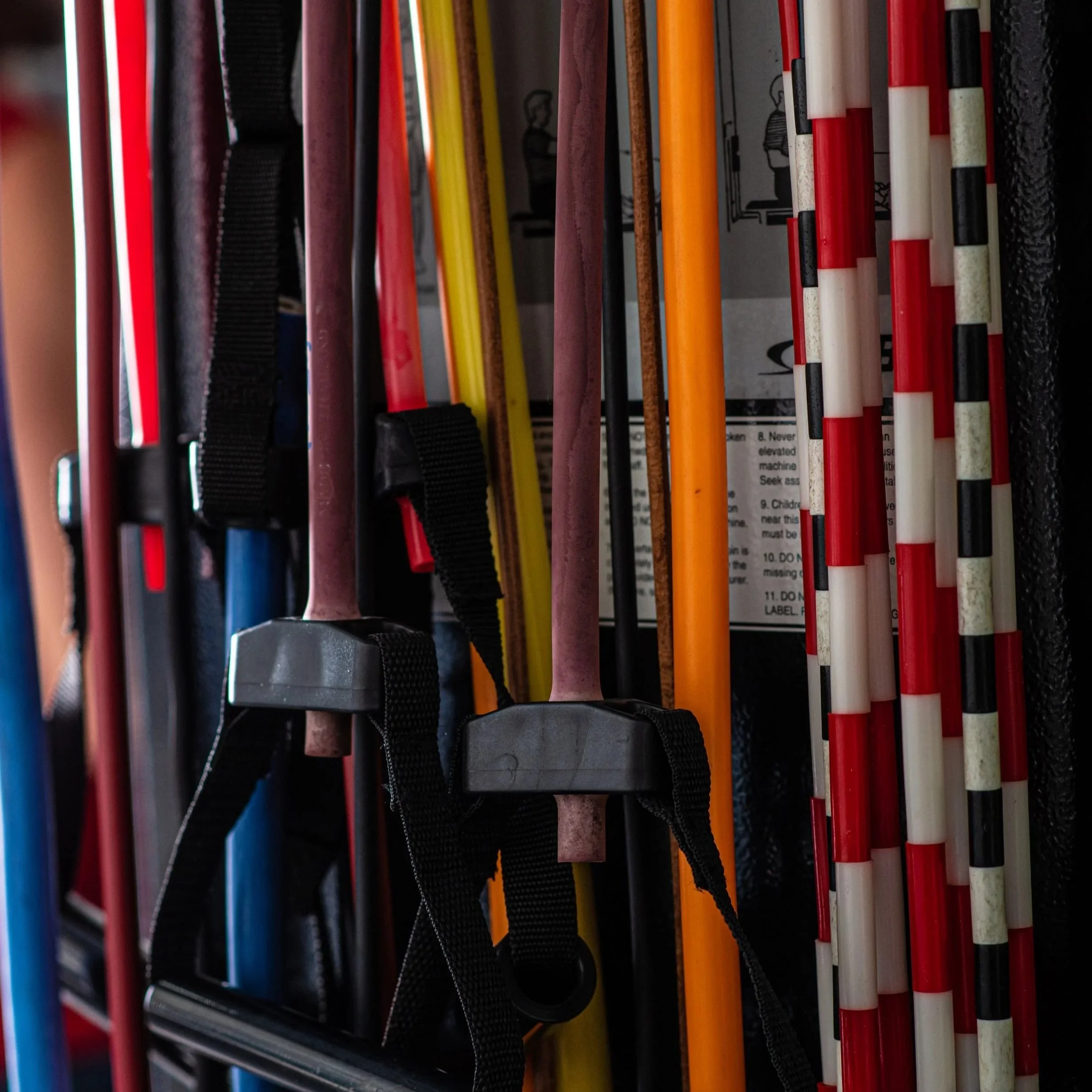 Close-up of a rack of hockey sticks in various colors and sizes, stored vertically.