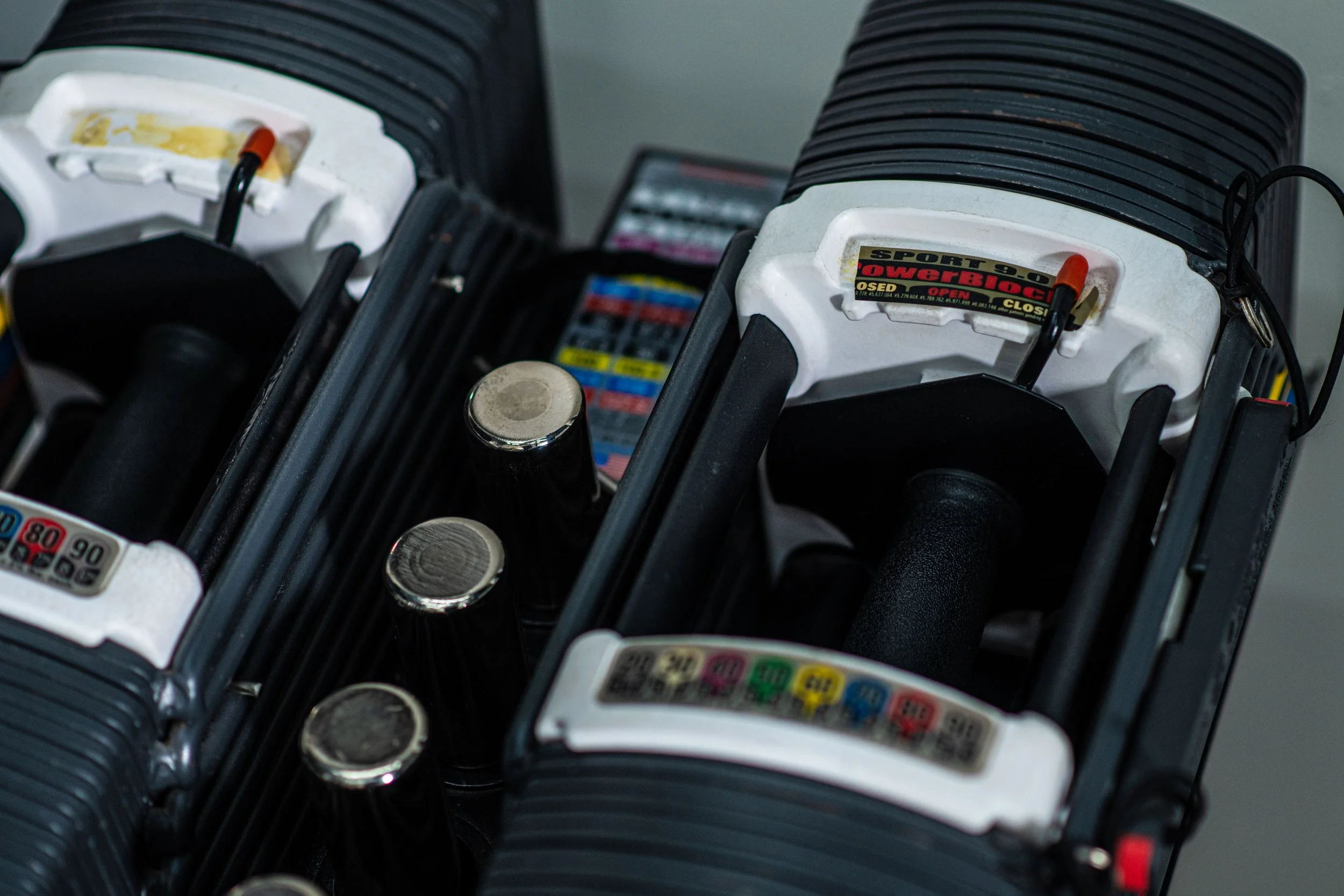 Close-up of two racing pistons with black fins and white tops, with a background of blurred racing decals and a gear shift selector.