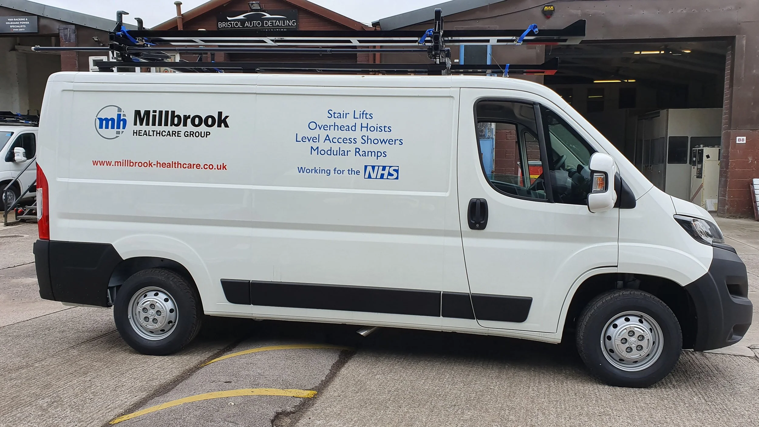 White service van with company branding for Millbrook Healthcare Group parked outside a building.