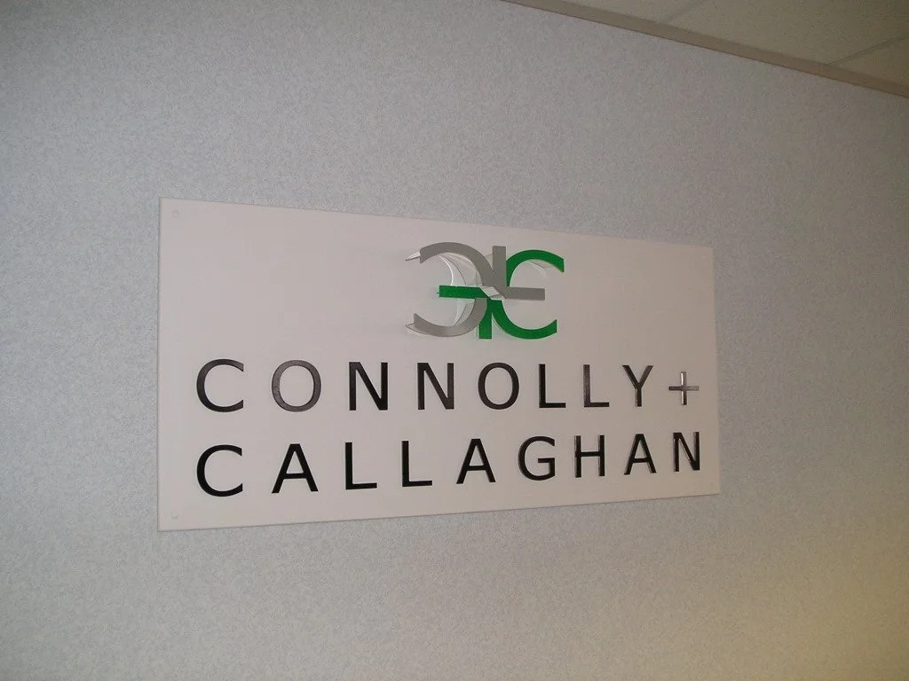 Sign with the logo and name of Connolly + Callaghan law firm on a wall.