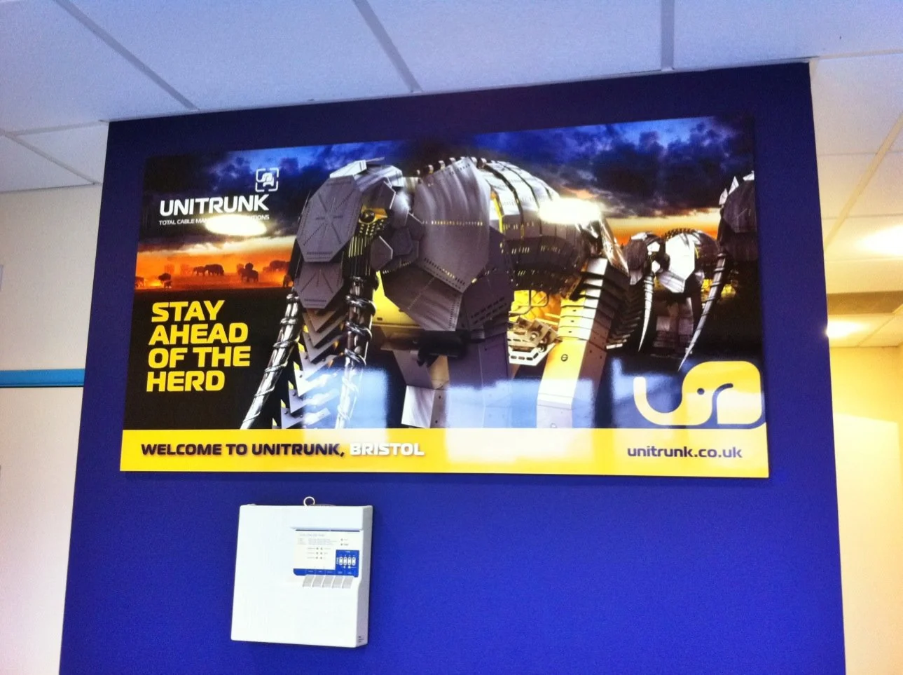 A large promotional poster for UnitTrunk features a robot made from industrial containers with a sunset background. The text on the poster reads "Stay Ahead of the Herd" and "Welcome to UnitTrunk, Bristol." The website address unitrunk.co.uk is also 