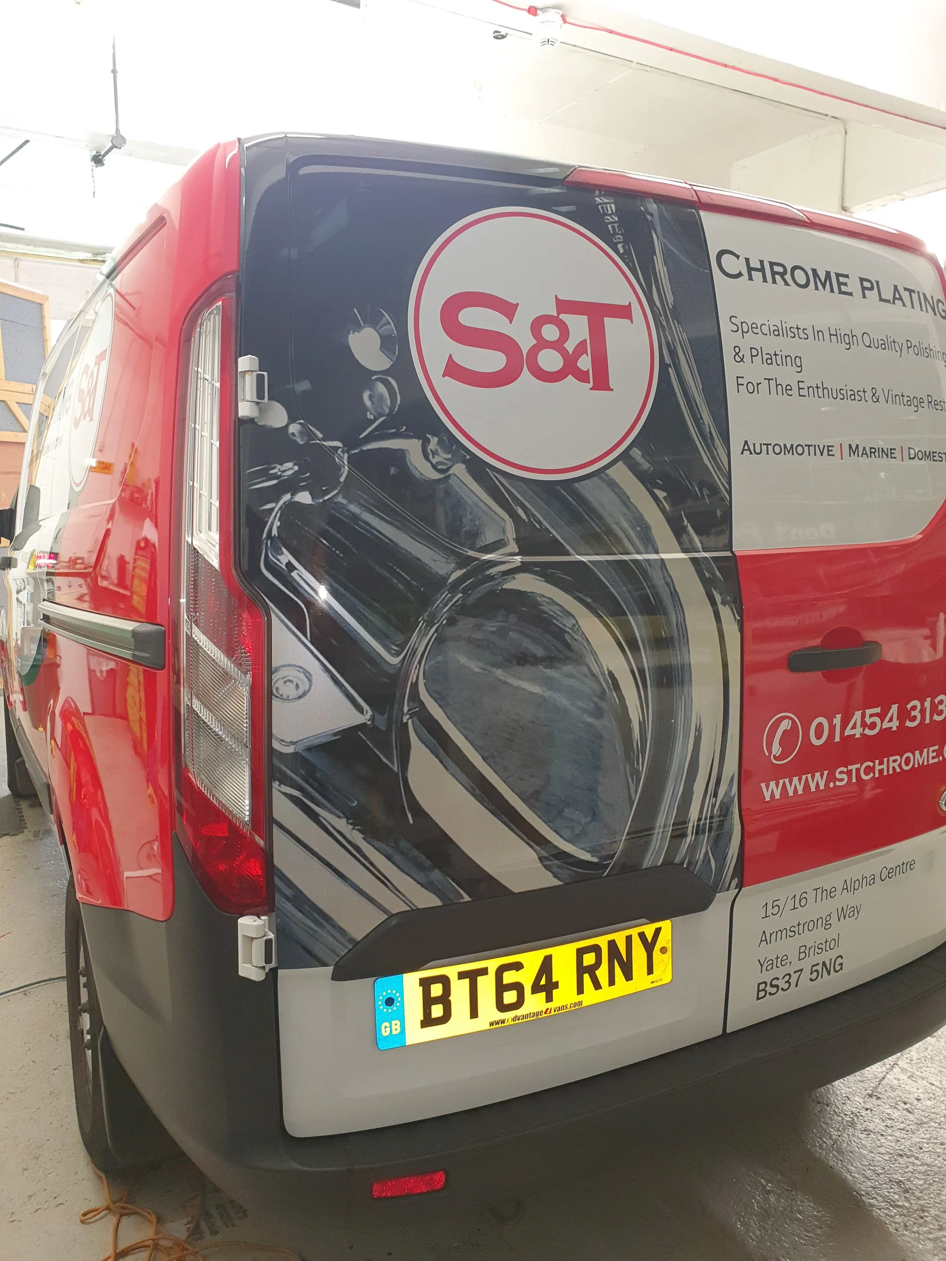 The back of a van with advertising for S&T Chrome Plating, including contact information, a slogan about high-quality polishing and plating, and a license plate reading 'BT64 RNY'.