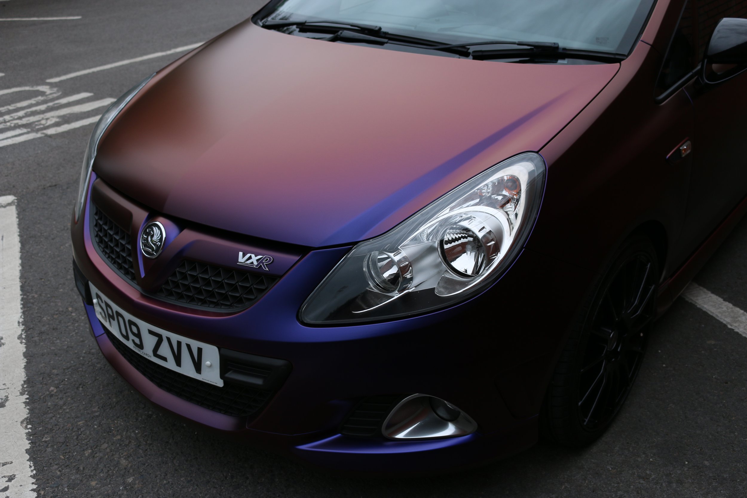 A maroon Vauxhall car parked in a parking lot with a license plate reading S8009 ZV