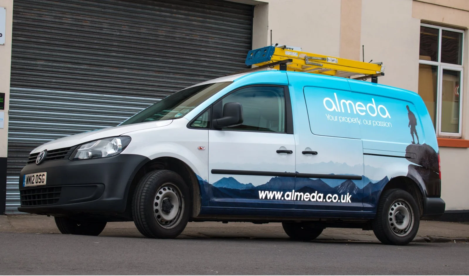 A white work van with branding for Almeda property services, featuring mountain landscape graphics and the slogan 'Your property, our passion.' A yellow ladder is mounted on top of the van.