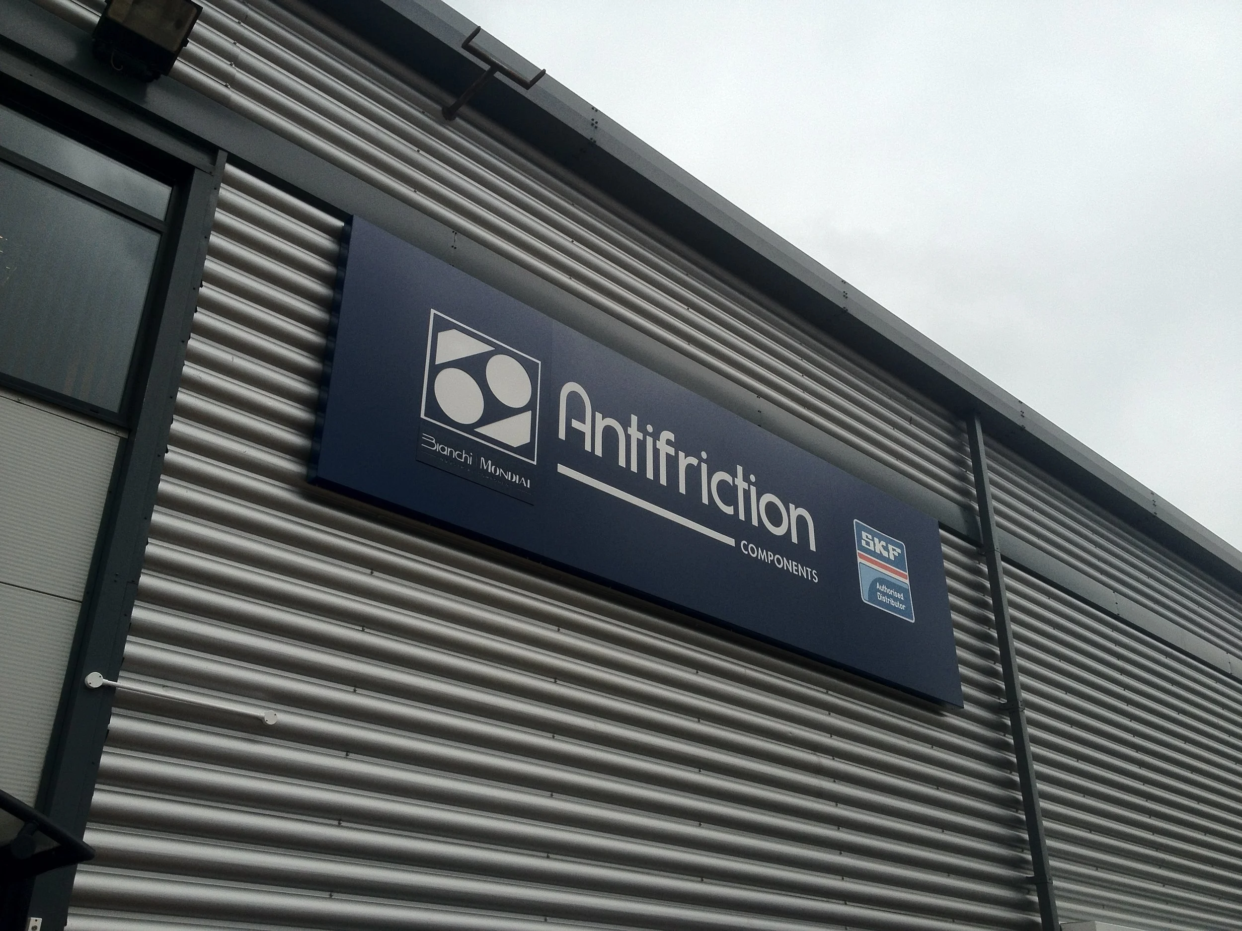 A building exterior with corrugated metal siding and a sign reading 'Antifriction Components' with logos of Bianchi Mondial and SKF.