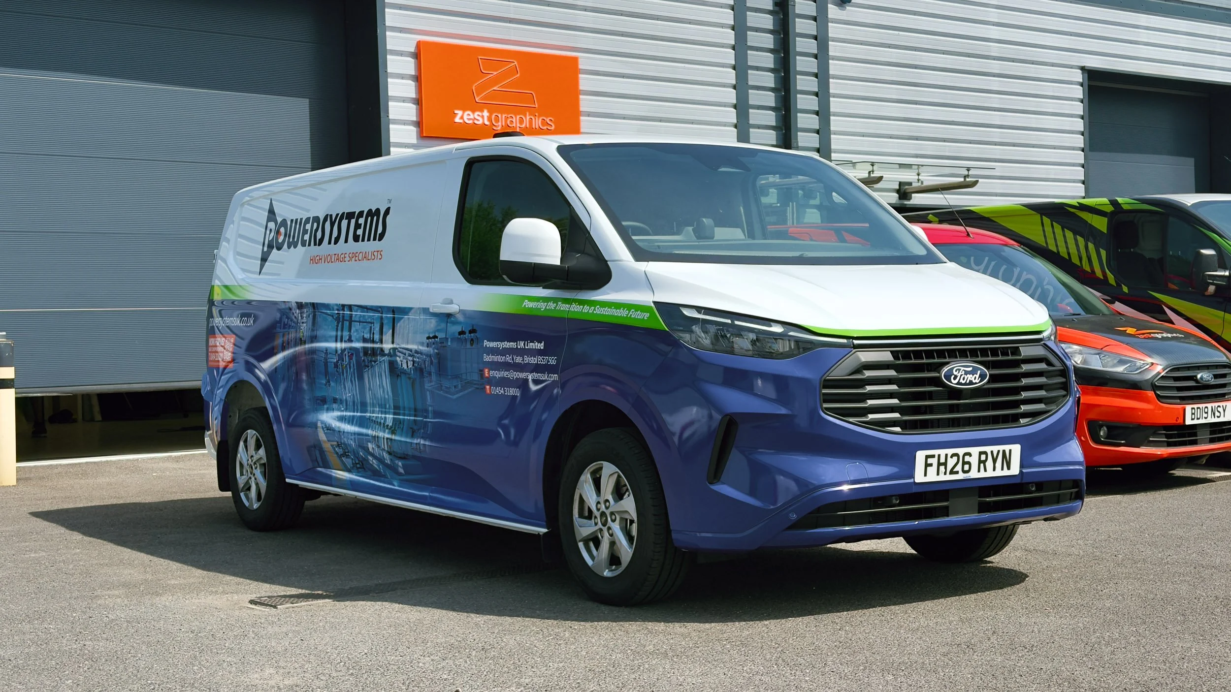 Blue Ford Transit van with vehicle wrap for Power Systems, parked in front of zest graphics installation centre