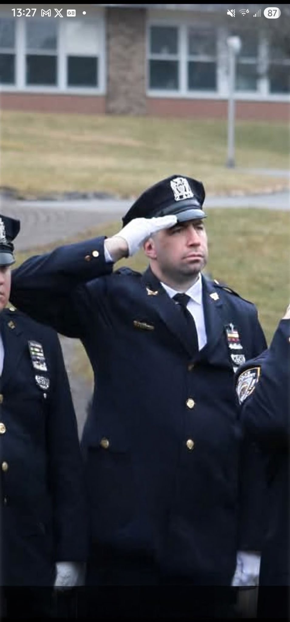 A uniformed police officer saluting during a ceremony.