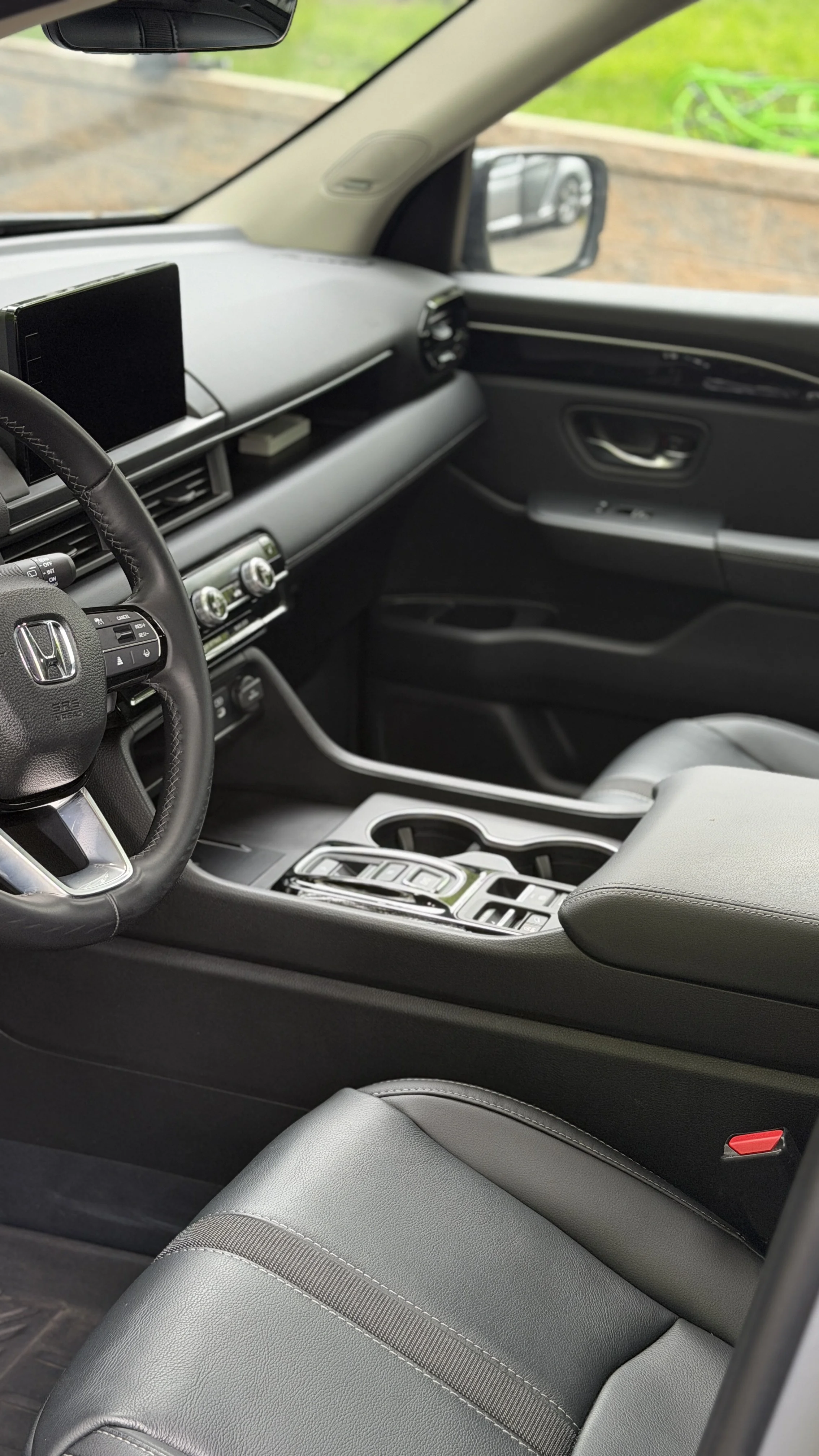 Interior of a modern car showing the steering wheel, dashboard, center console, and front passenger seat with leather upholstery.