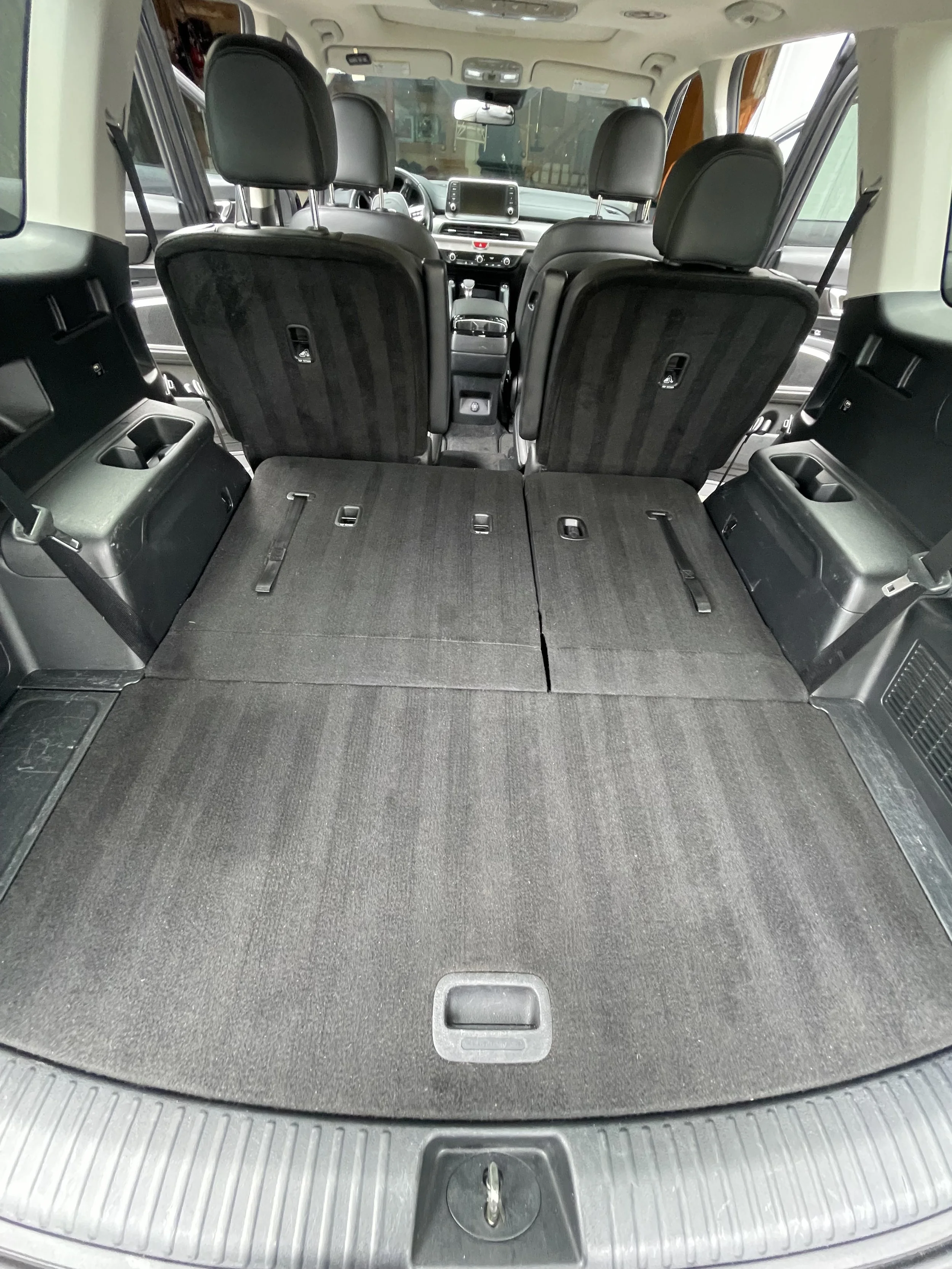 The interior of an SUV showing the rear seats folded down to increase cargo space, with a view of the back of the front seats and the dashboard.