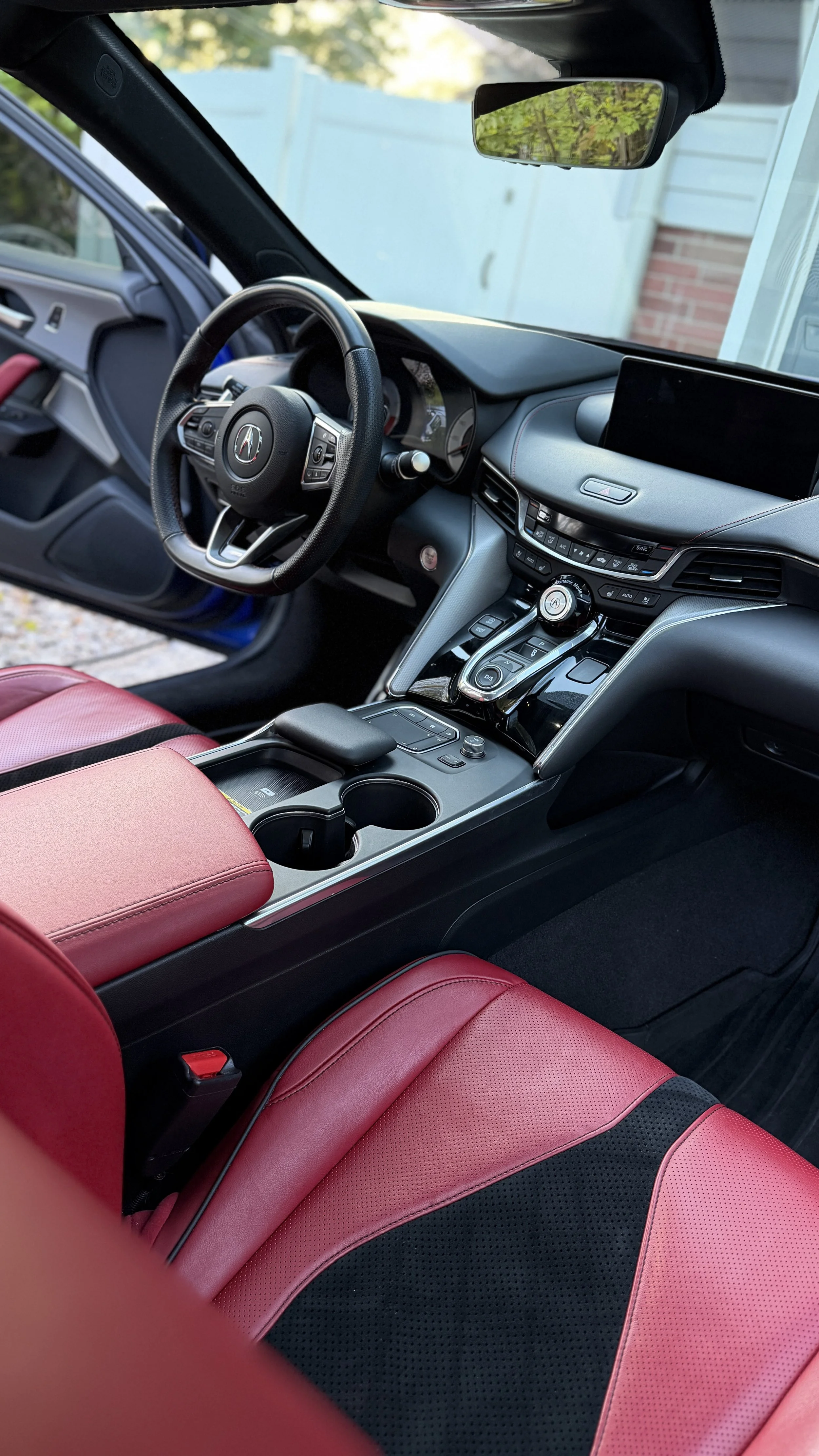 Interior of a modern car with red and black leather seats, a black dashboard, and a steering wheel.
