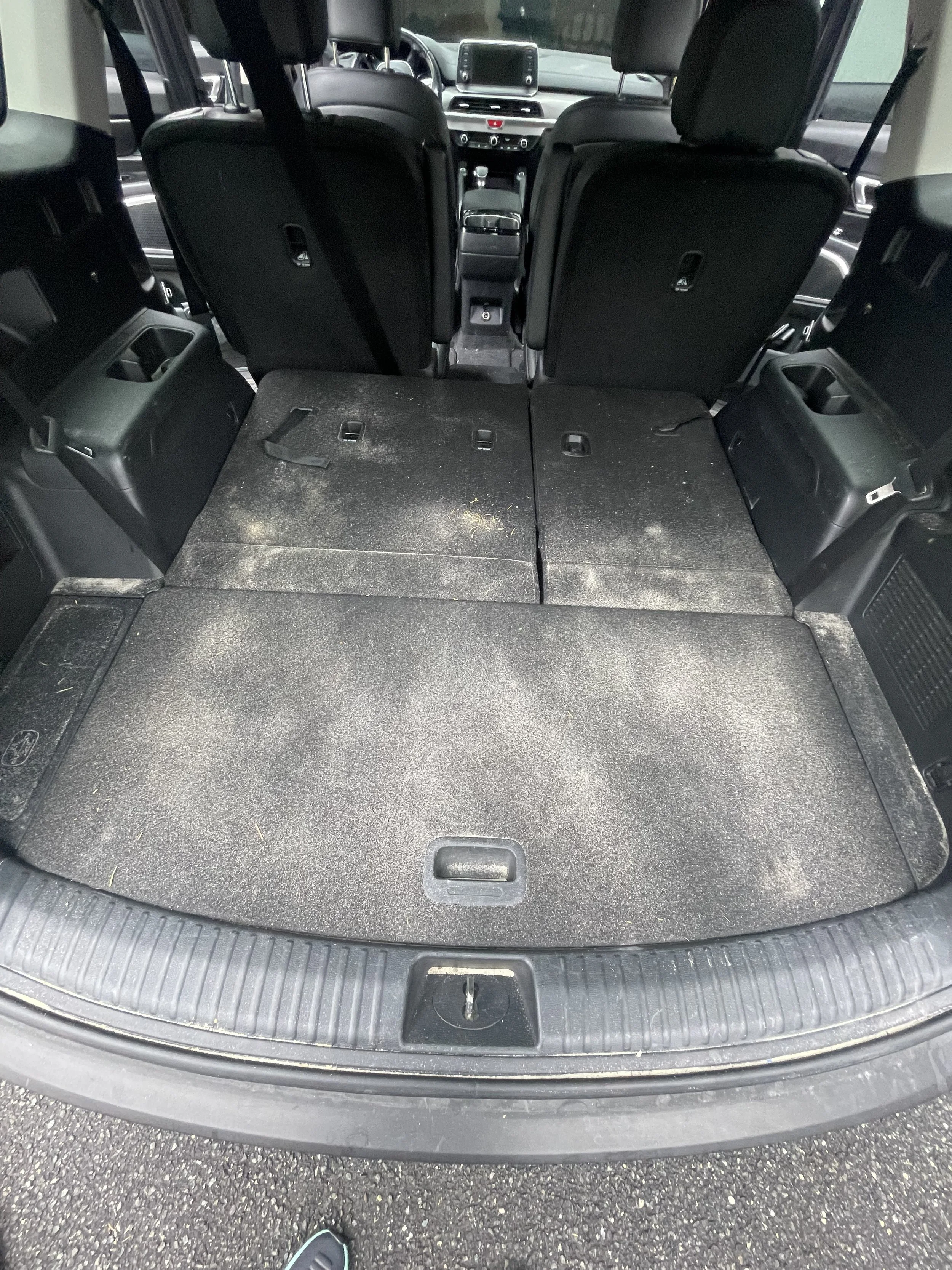 Empty black interior of a vehicle's trunk with folded rear seats and visible floor space.