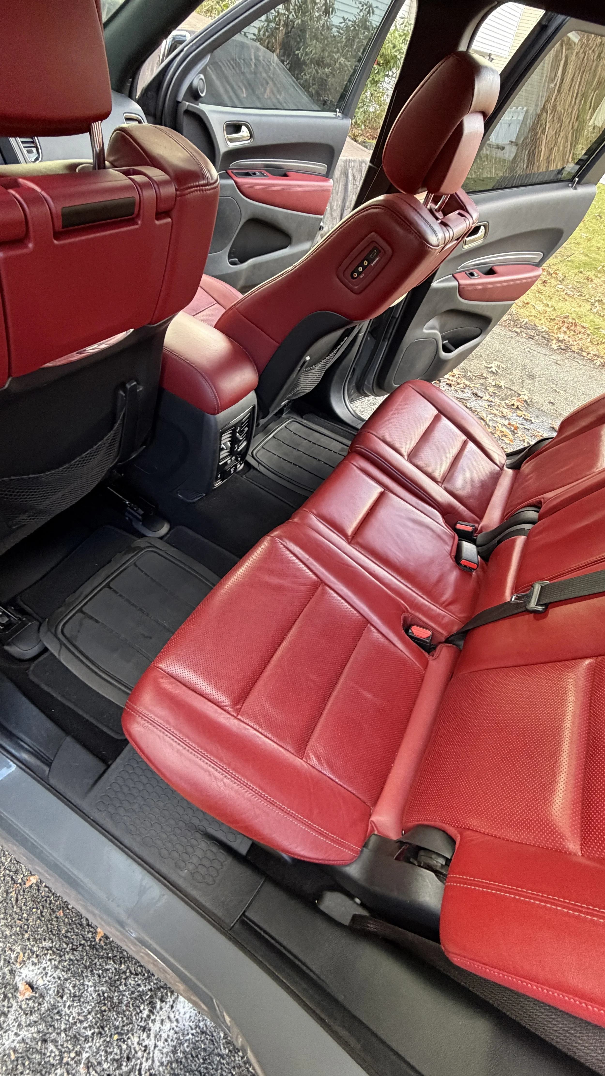 Inside a vehicle with red leather seats, black floor mats, and gray and red interior door panels.