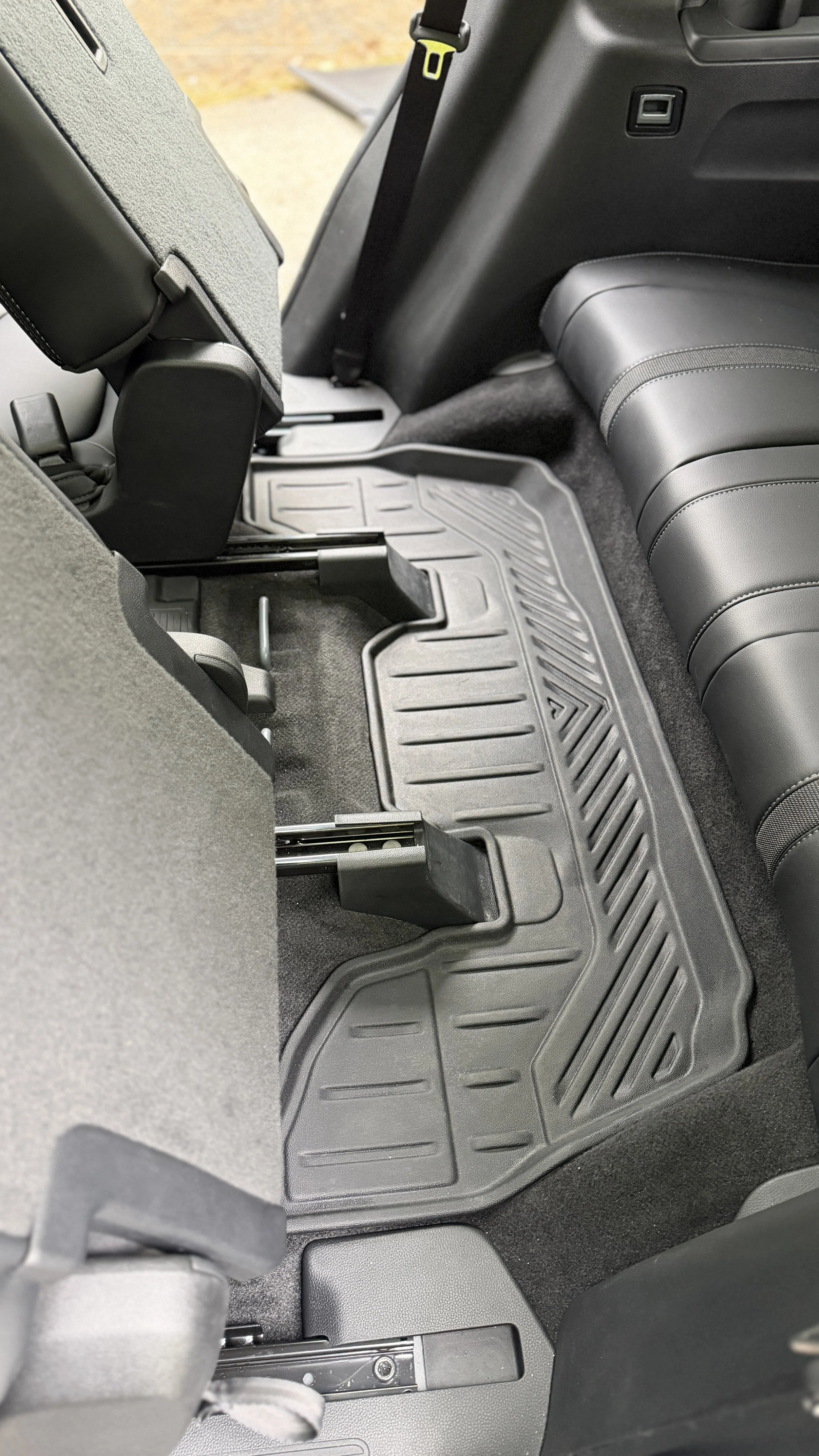 The back seat area of a vehicle showing the floor mat, part of the rear seats, and part of the front passenger seat.