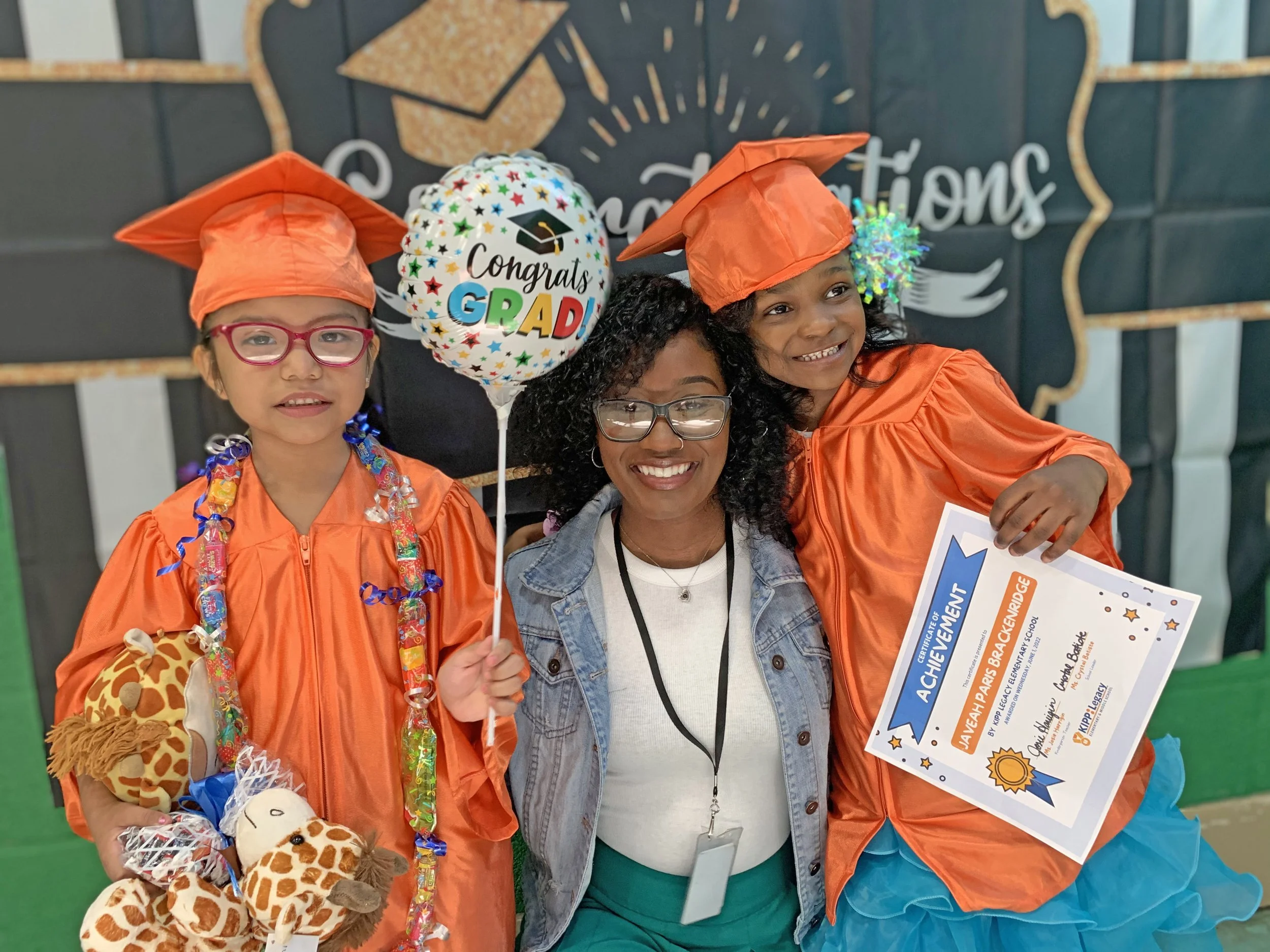 Our Assistant School Leader, Ms. Josie Harrigin, hugging two Kindergarten graduates.
