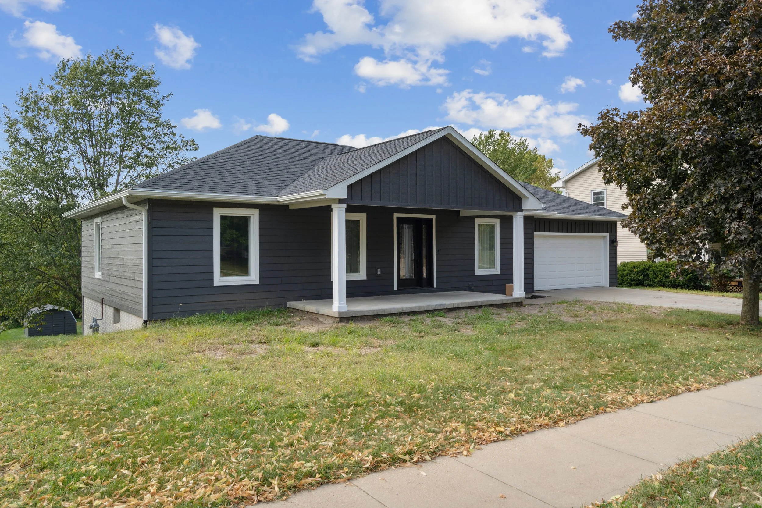 Professional vinyl siding installation on a residential home in Iowa City, IA featuring dark siding and white trim accents.
