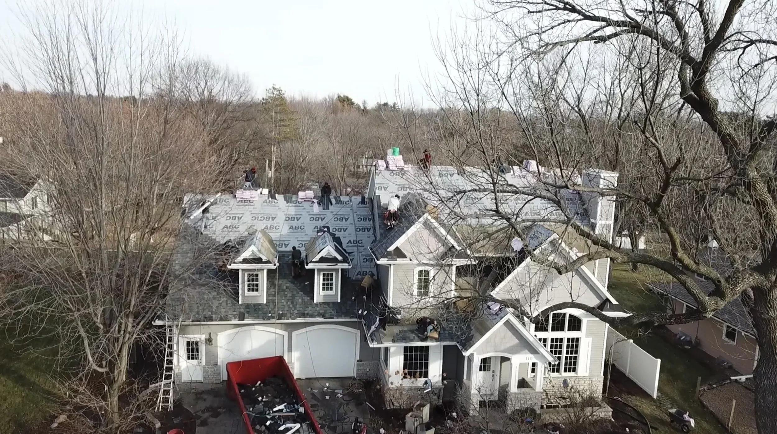 Roofing crew installing a new asphalt shingle roof on a large home in Iowa City, IA during a complete roof replacement project.