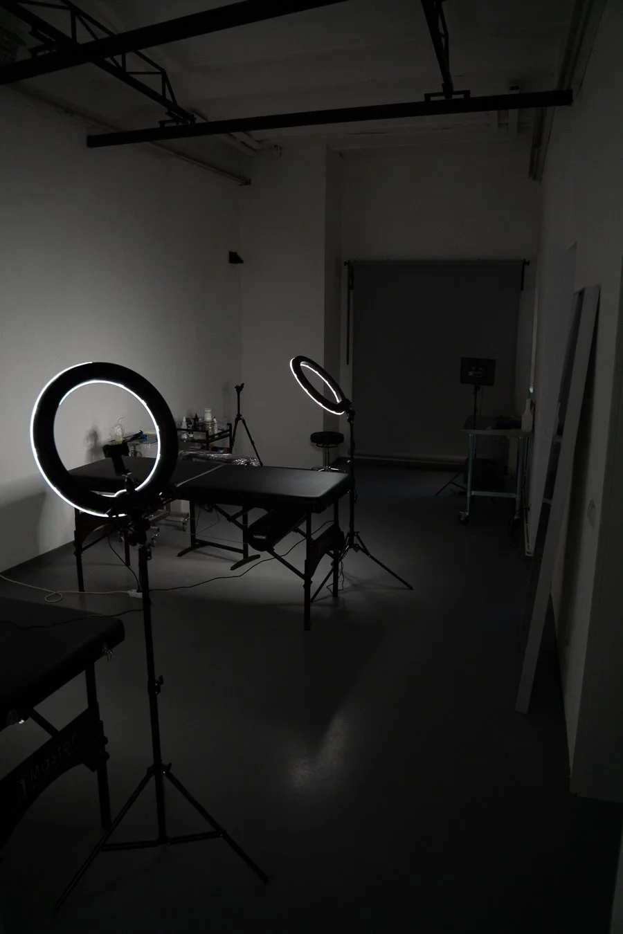 A photography studio with professional lighting equipment, a black table, and a closed backdrop in a dark room.