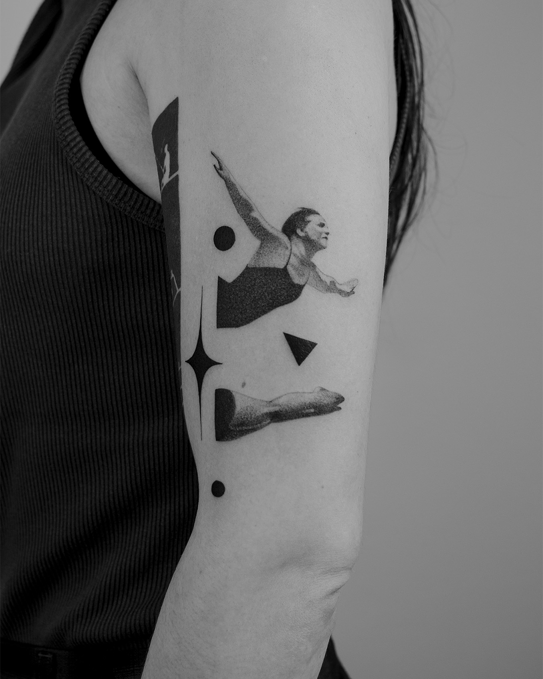 Tattoo of a woman in a swimming pose with geometric shapes on upper arm.