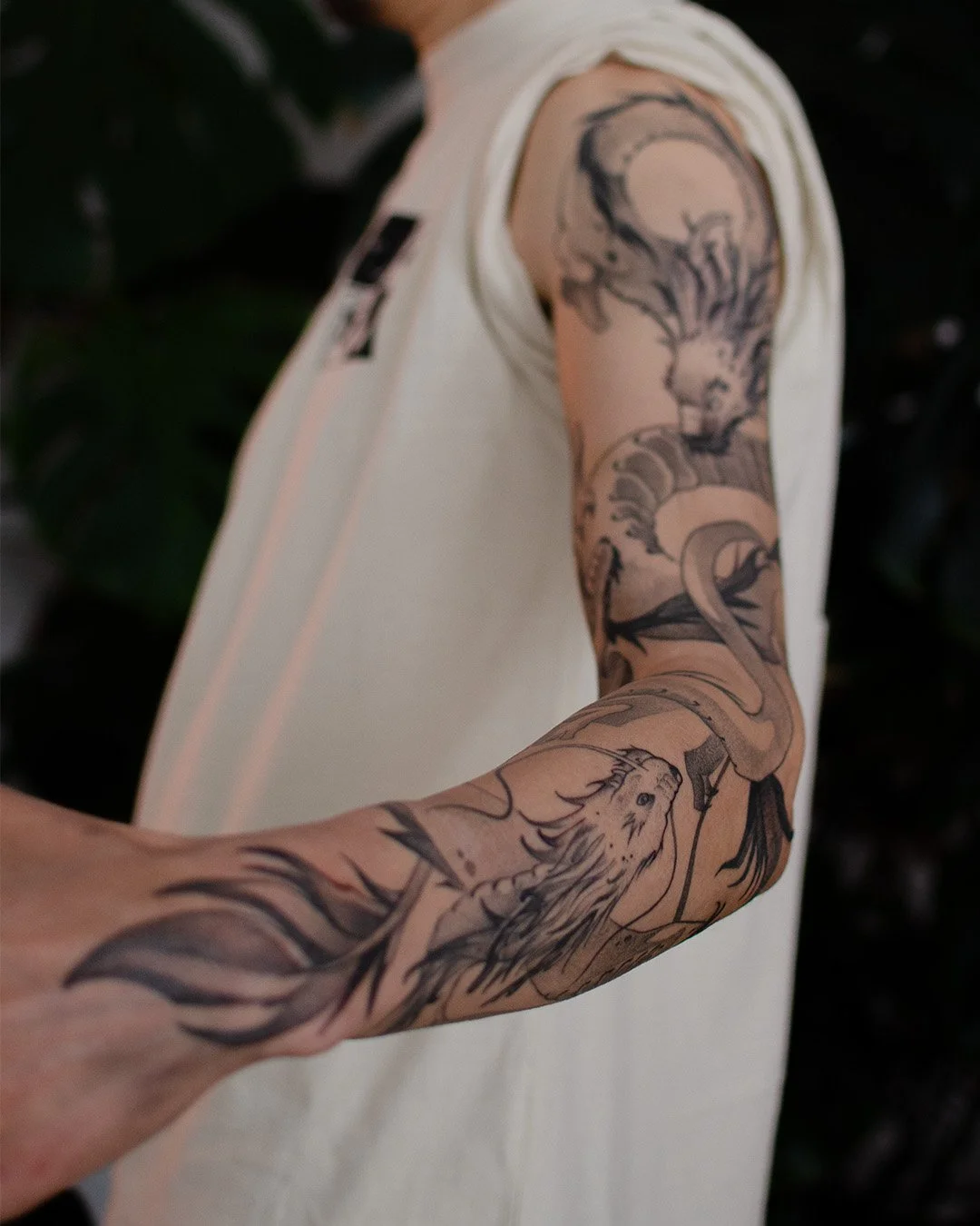 A tattooed arm with a lion and a dragon tattoo.