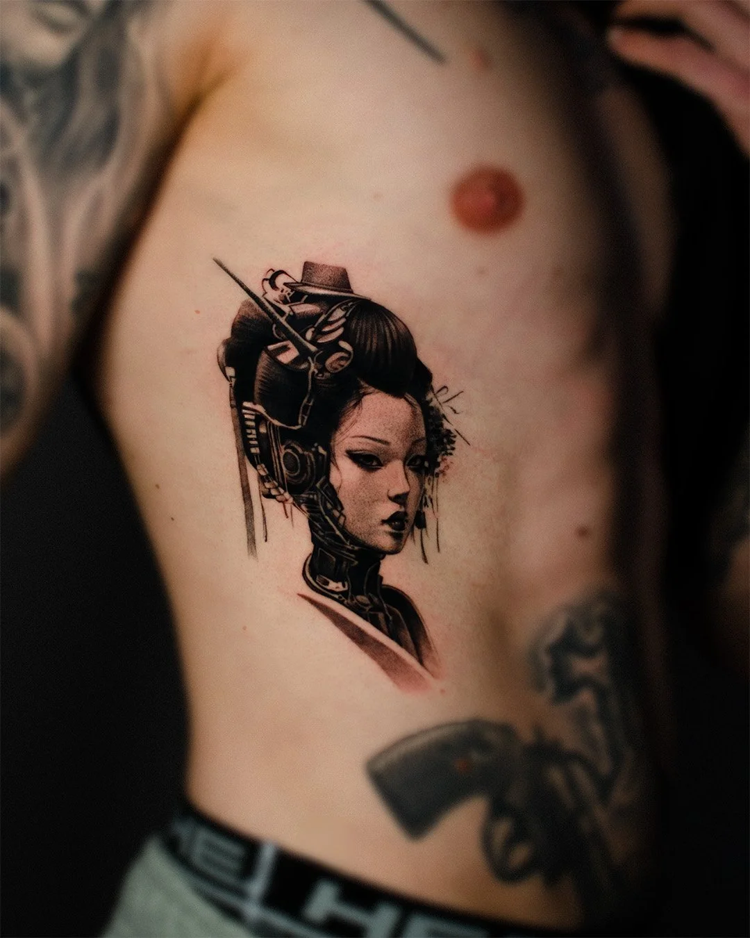 Tattoo of a cyberpunk woman with traditional hair and makeup, combined with robotic and futuristic elements on her head and neck, on person's upper chest.