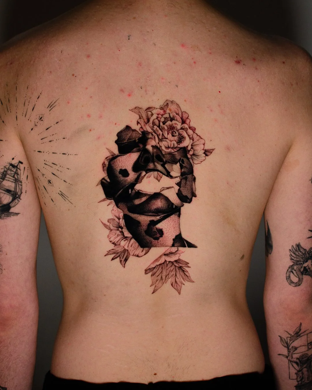 Tattoo of a woman's face with floral and butterfly designs on chest and arms.