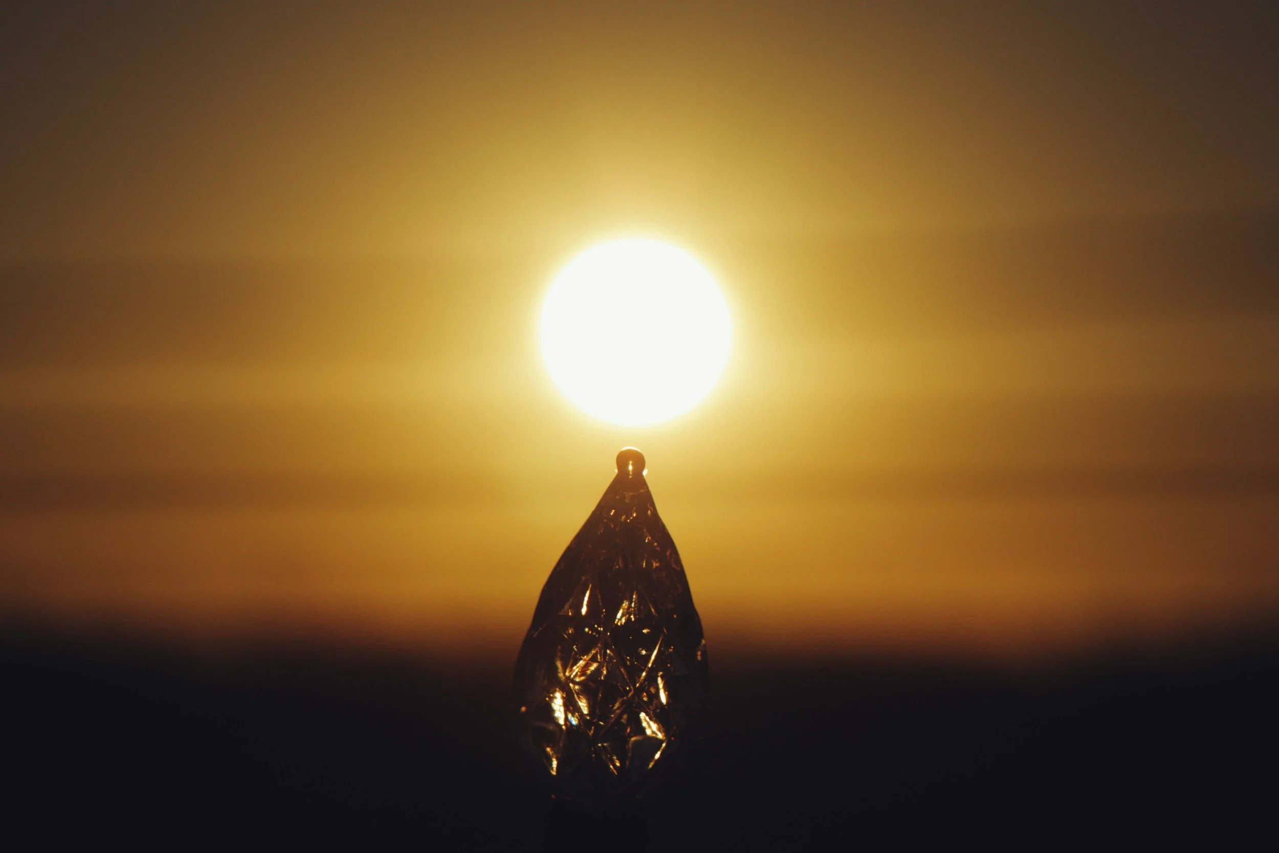 A single teardrop held up to the sun with light shining through it, representing the energy of grief moving again
