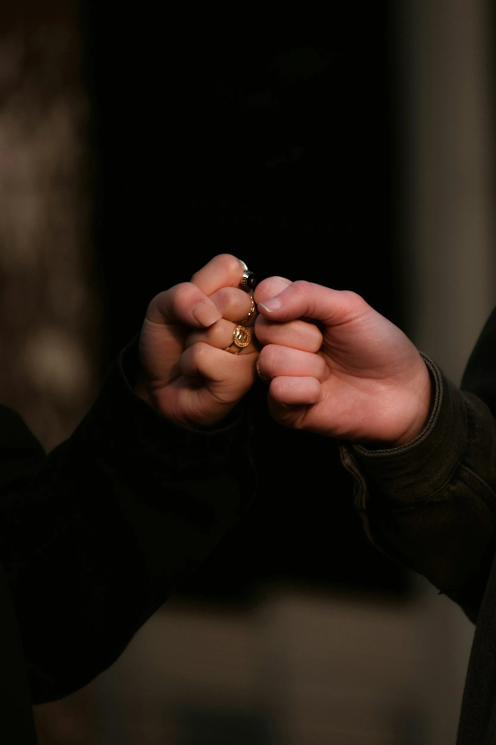 Personne tenant une bague en or entre ses doigts, fond noir