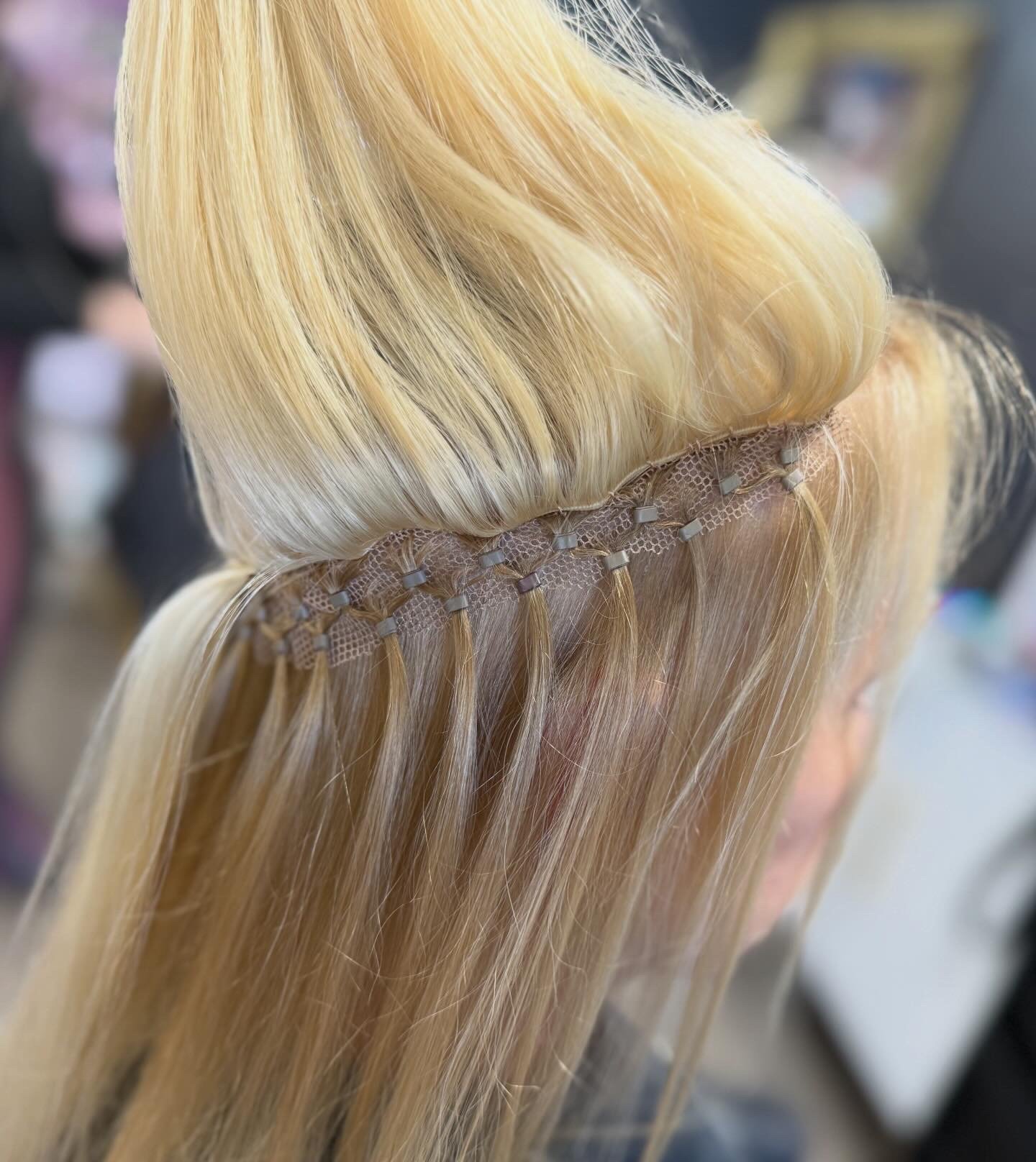 Blonde hair sectioned with hair clips, in a salon or hairstylist's workspace.