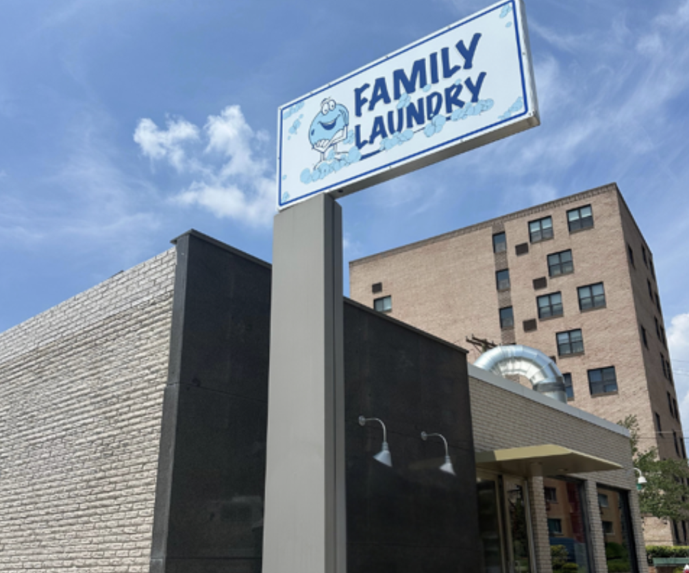Family laundry sign with cartoon washing machine character outside a building.