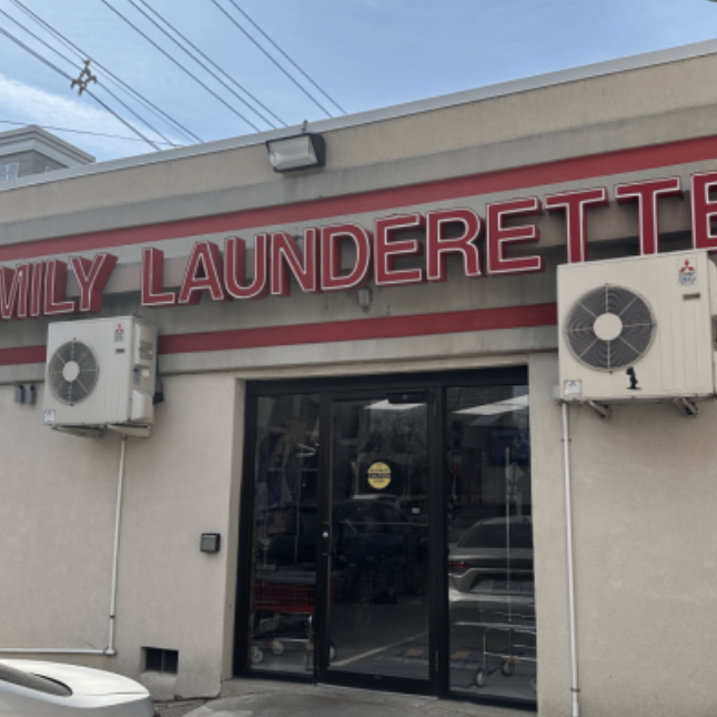 Exterior of a laundry business named Family Launderette with a glass door and two air conditioning units outdoors.