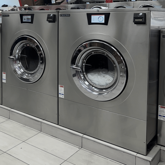 Two front-loading commercial washing machines in a laundromat.