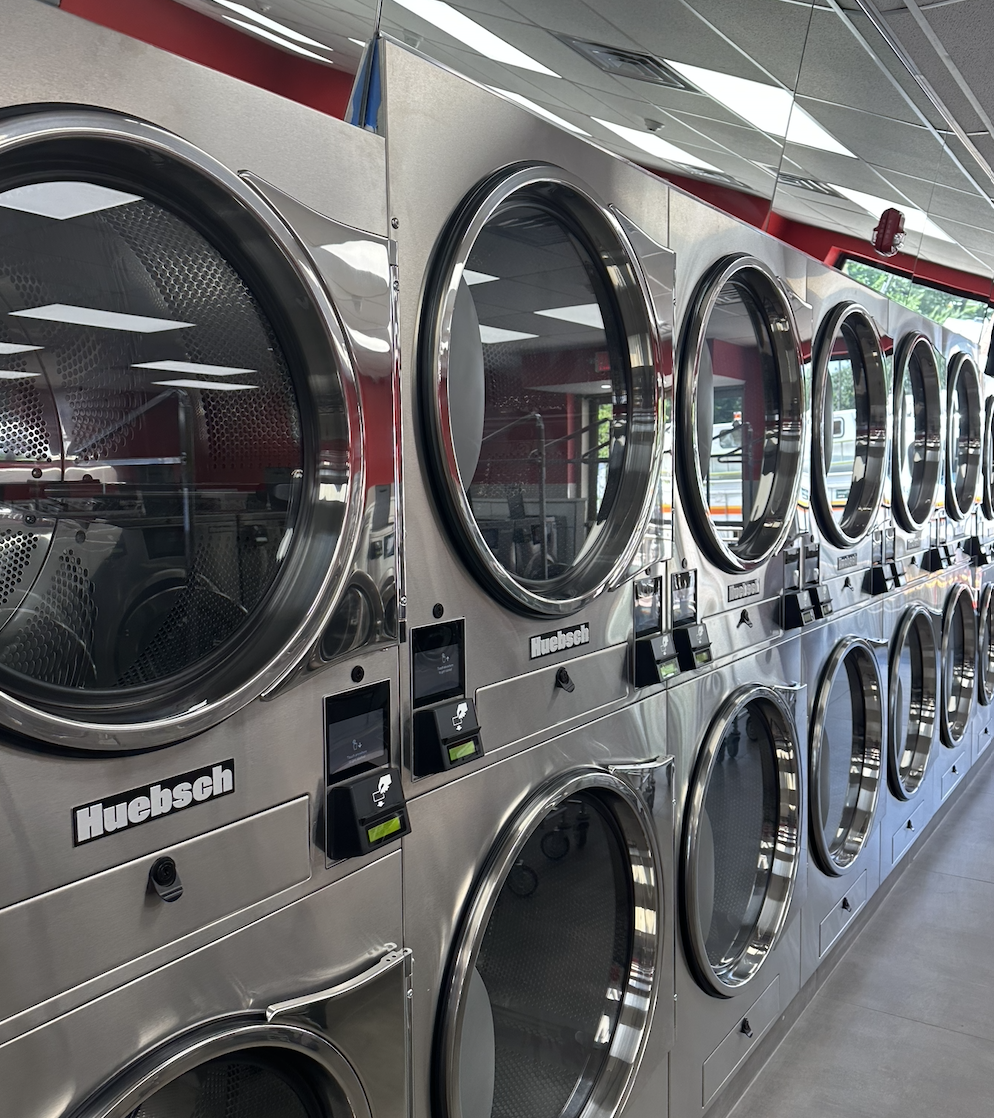 Row of commercial laundry washing machines in a laundromat.