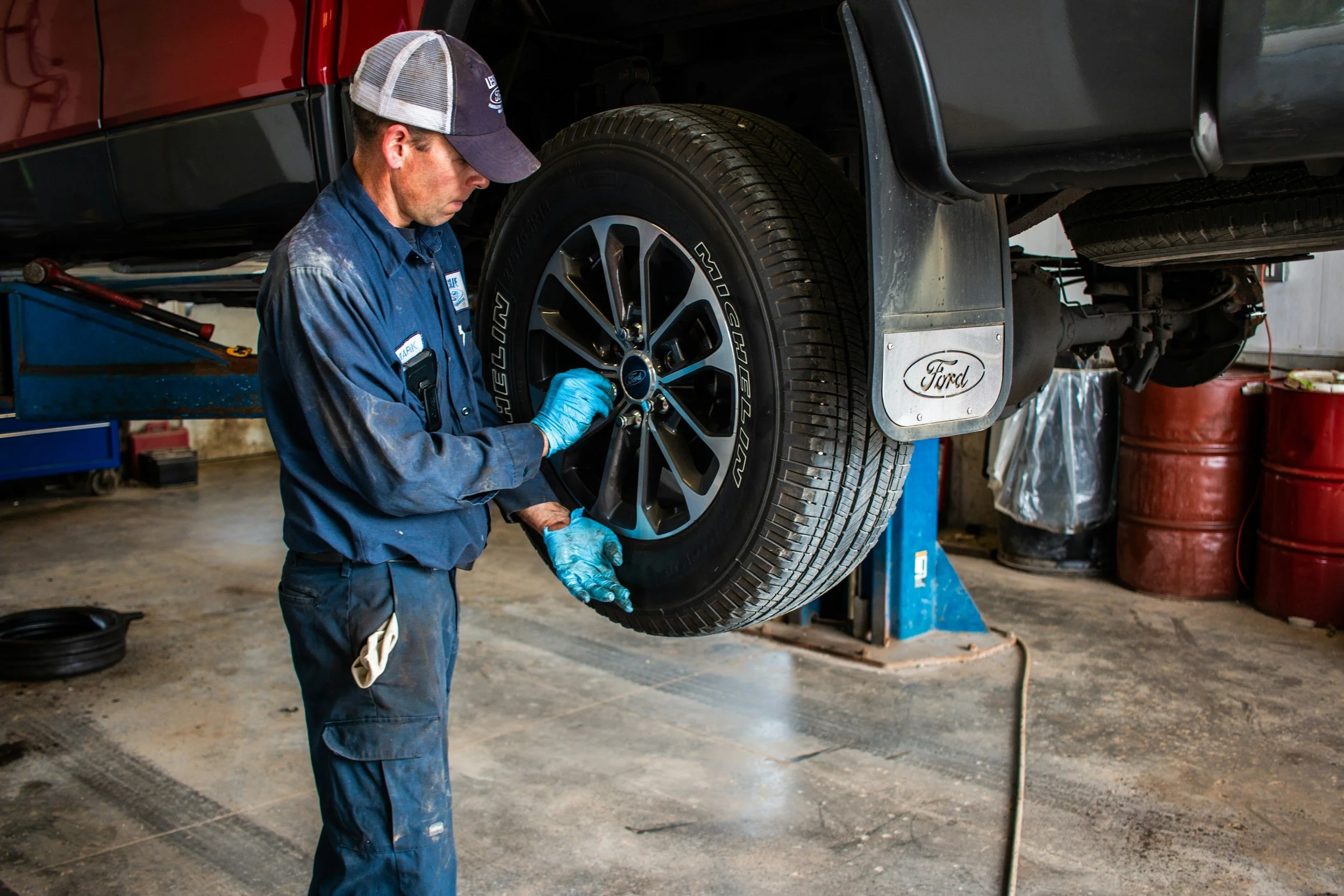 A mechanic inspecting a vehicle's wheel in an auto repair shop.