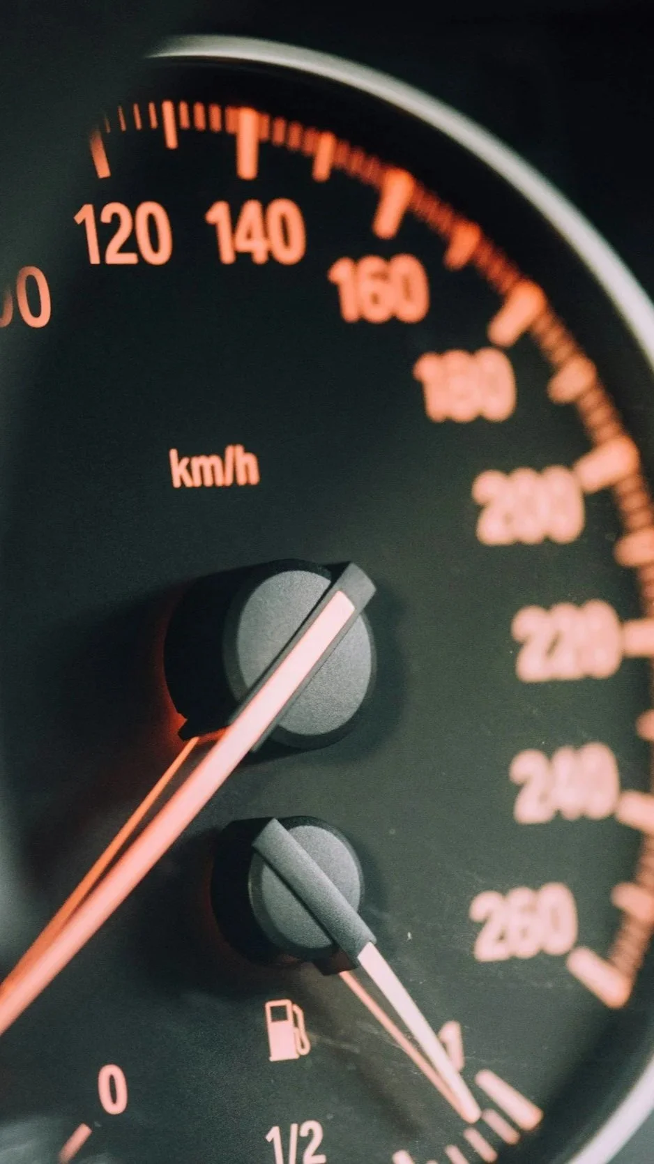 Close-up of a car's speedometer showing a speed of approximately 60 km/h, with the fuel gauge indicating less than half a tank.