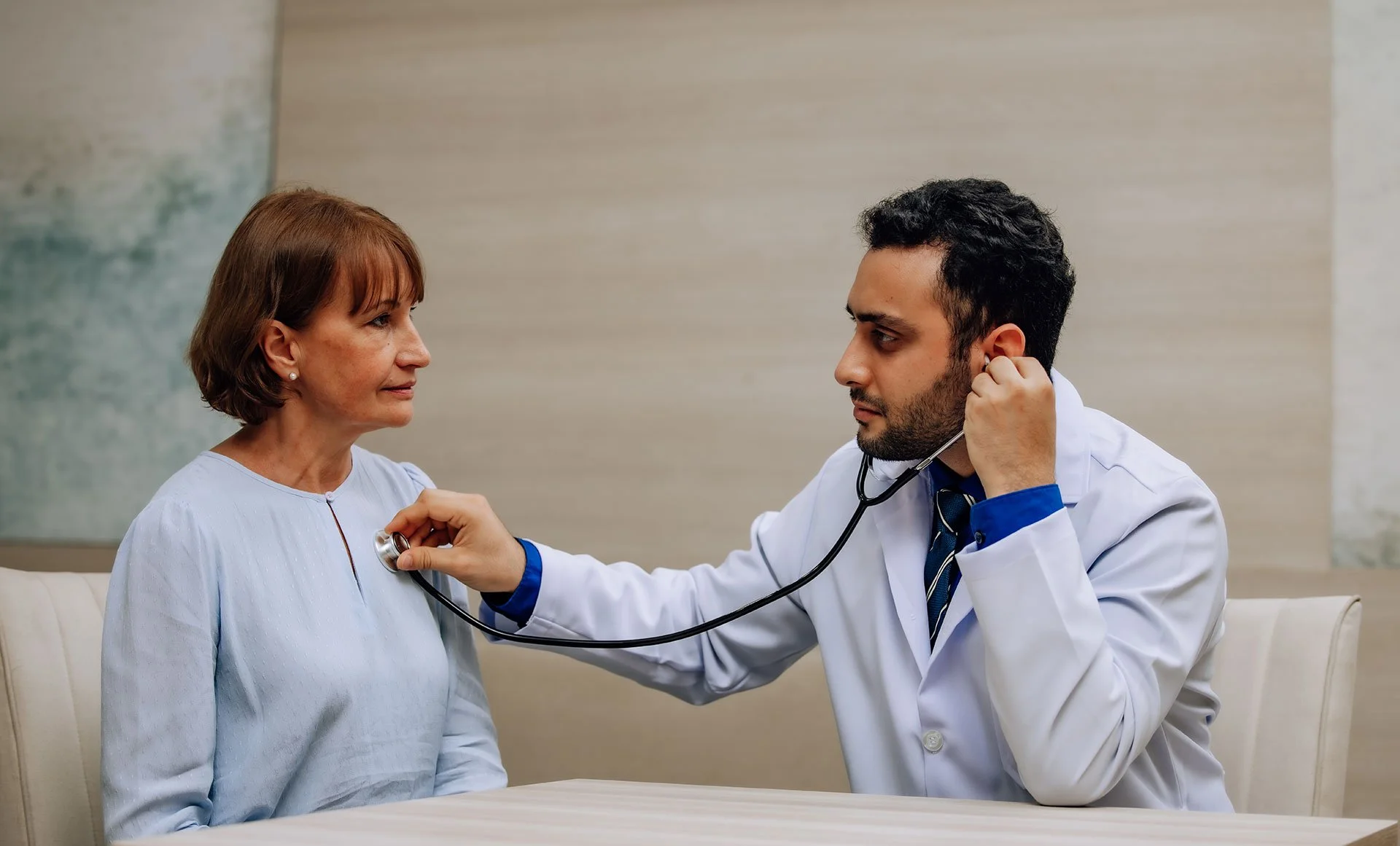 Un médico examina a una mujer mayor con un estetoscopio en una consulta médica.