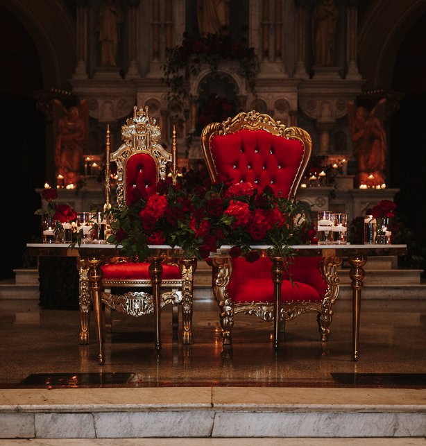 Gold and red ornate chairs with floral decorations in a church or cathedral setting.