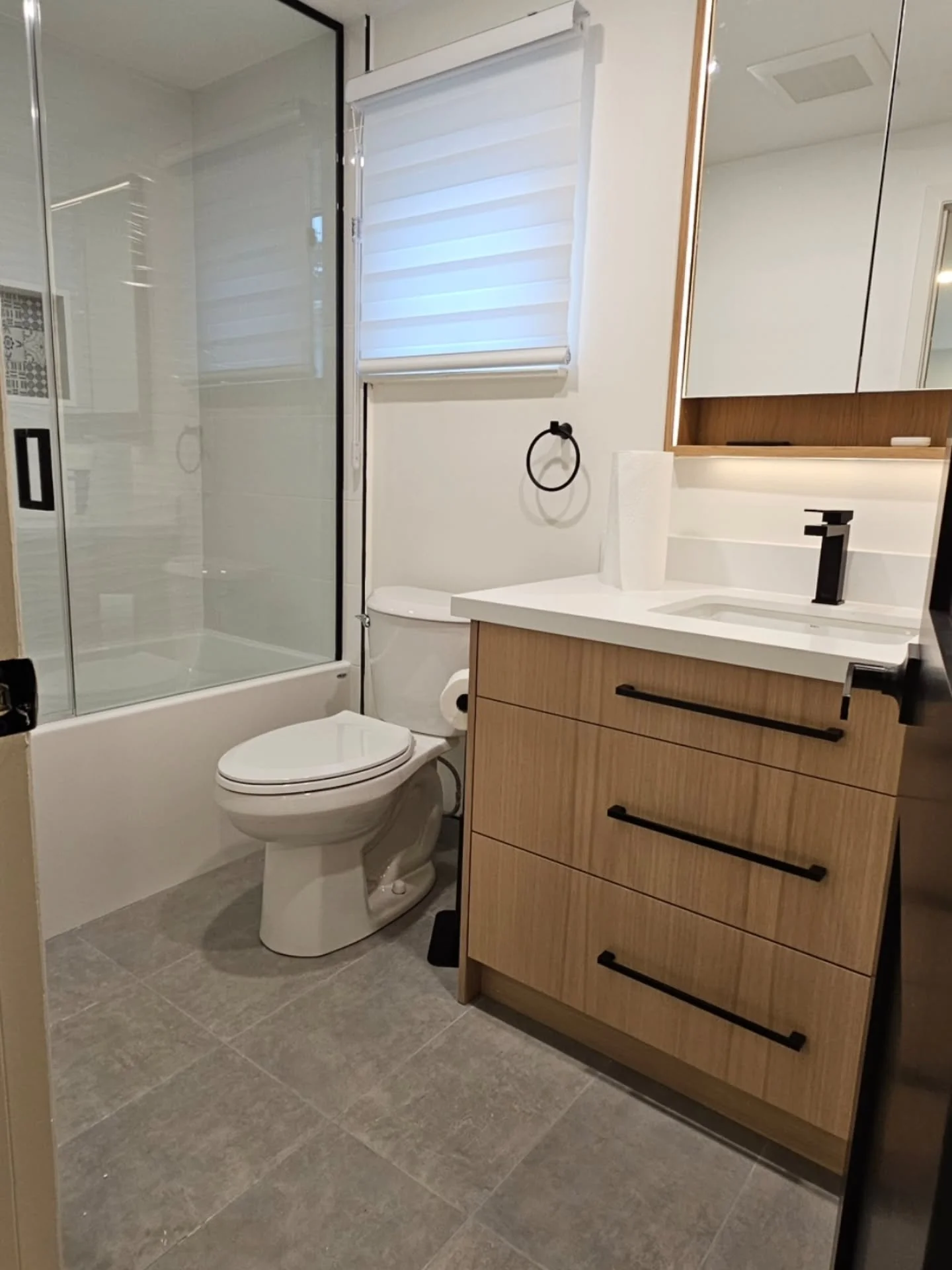 Warm oak tones meet crisp, modern lines. 

​We brought this bathroom to life by balancing natural textures with sharp, contemporary accents. From the light wood vanity and illuminated medicine cabinet to the matte black hardware and custom glass tub 
