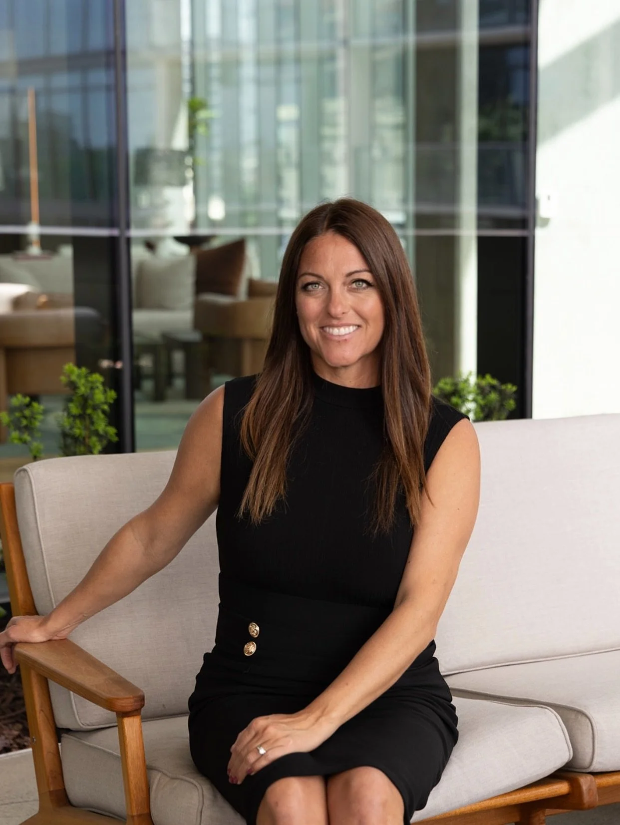 Woman with long brown hair relaxing in a modern glass-walled space with greenery, representing Seattle to Tennessee lifestyle and relocation journey